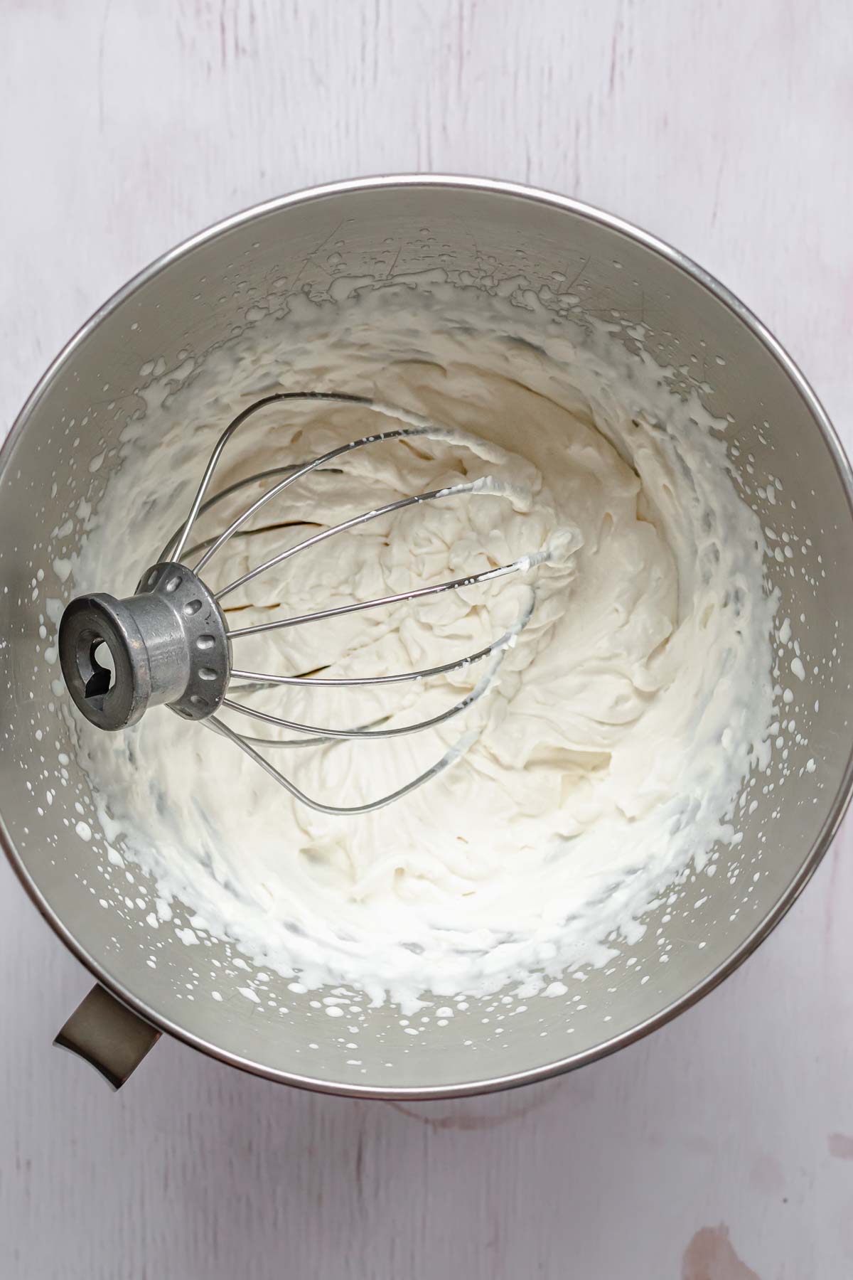 Whipped cream in a bowl with a whisk in it.
