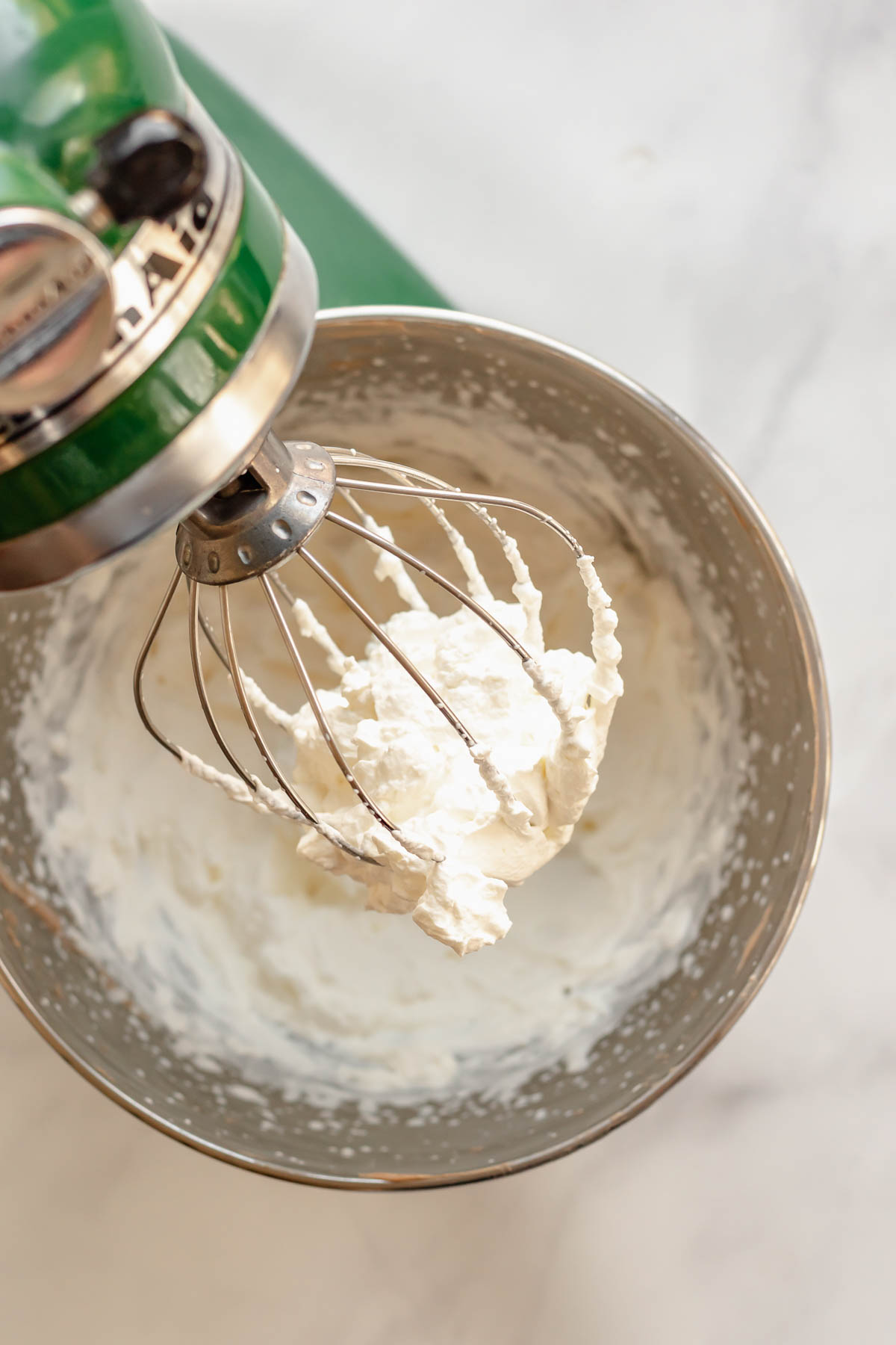 Whipped cream in the whisk of a stand mixer.