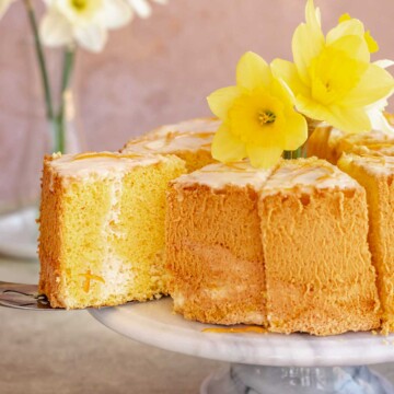 A slice of daffodil cake being removed from the cake stand with a pie spatula.