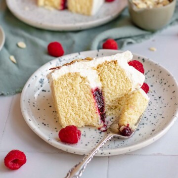 Almond raspberry cake slice on a plate. A fork remove a piece.