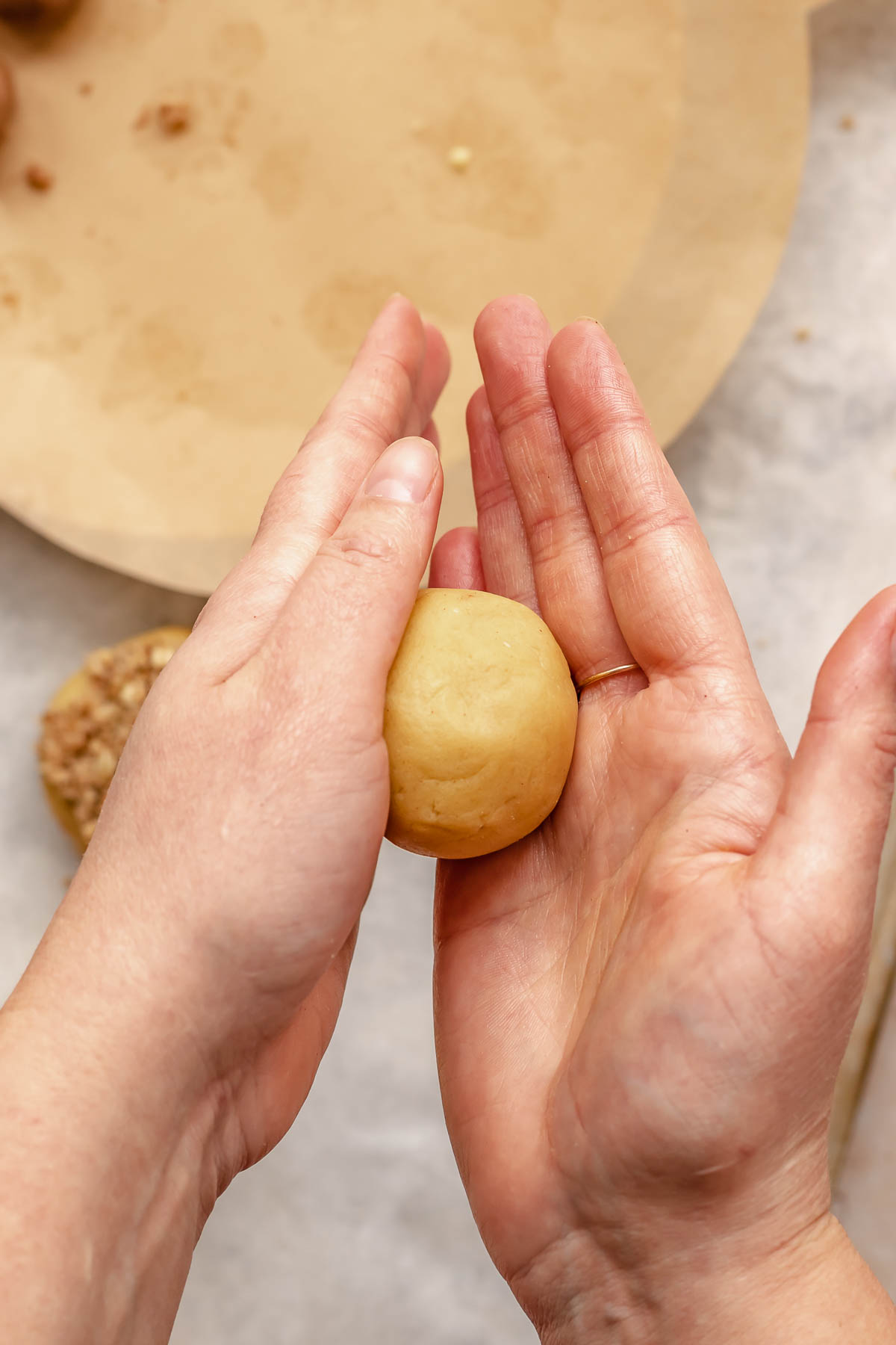 Hands roll a cookie dough ball.