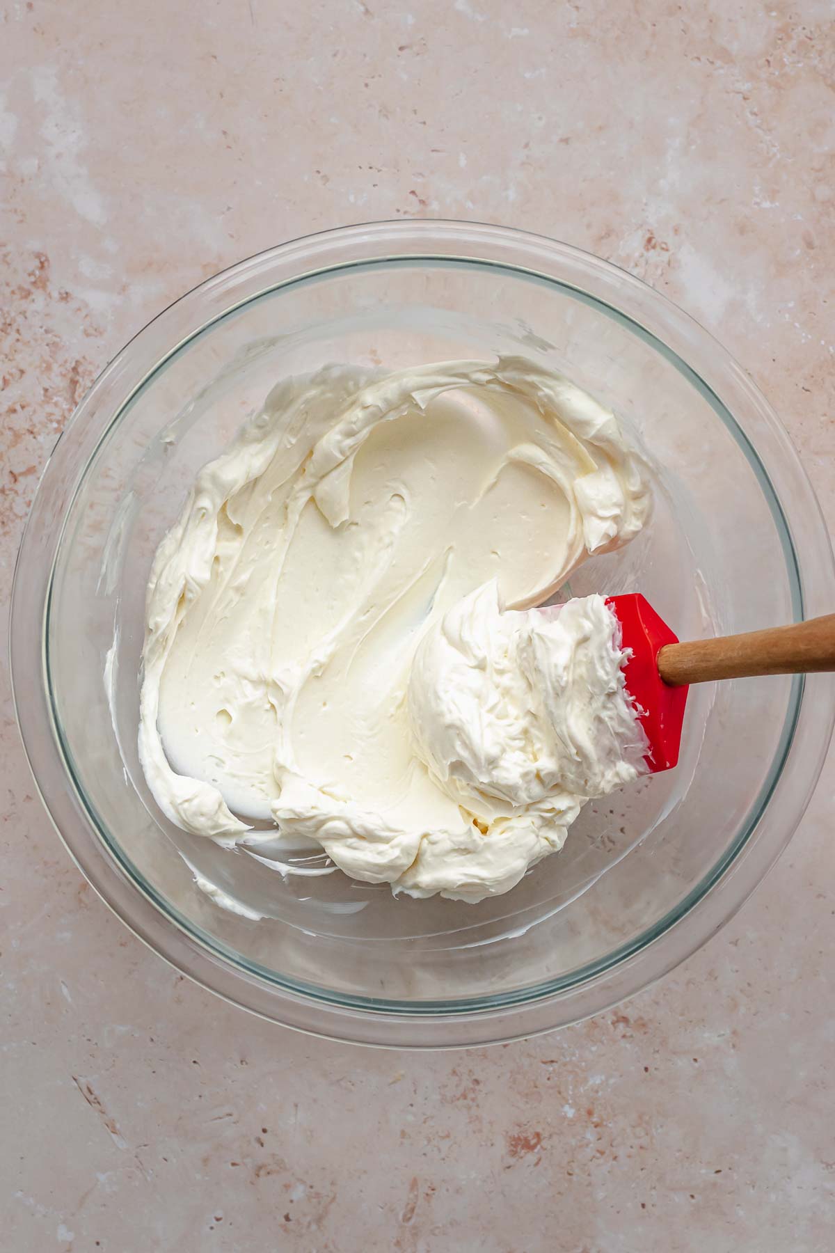 Cream cheese softened in a bowl with a spatula in it.