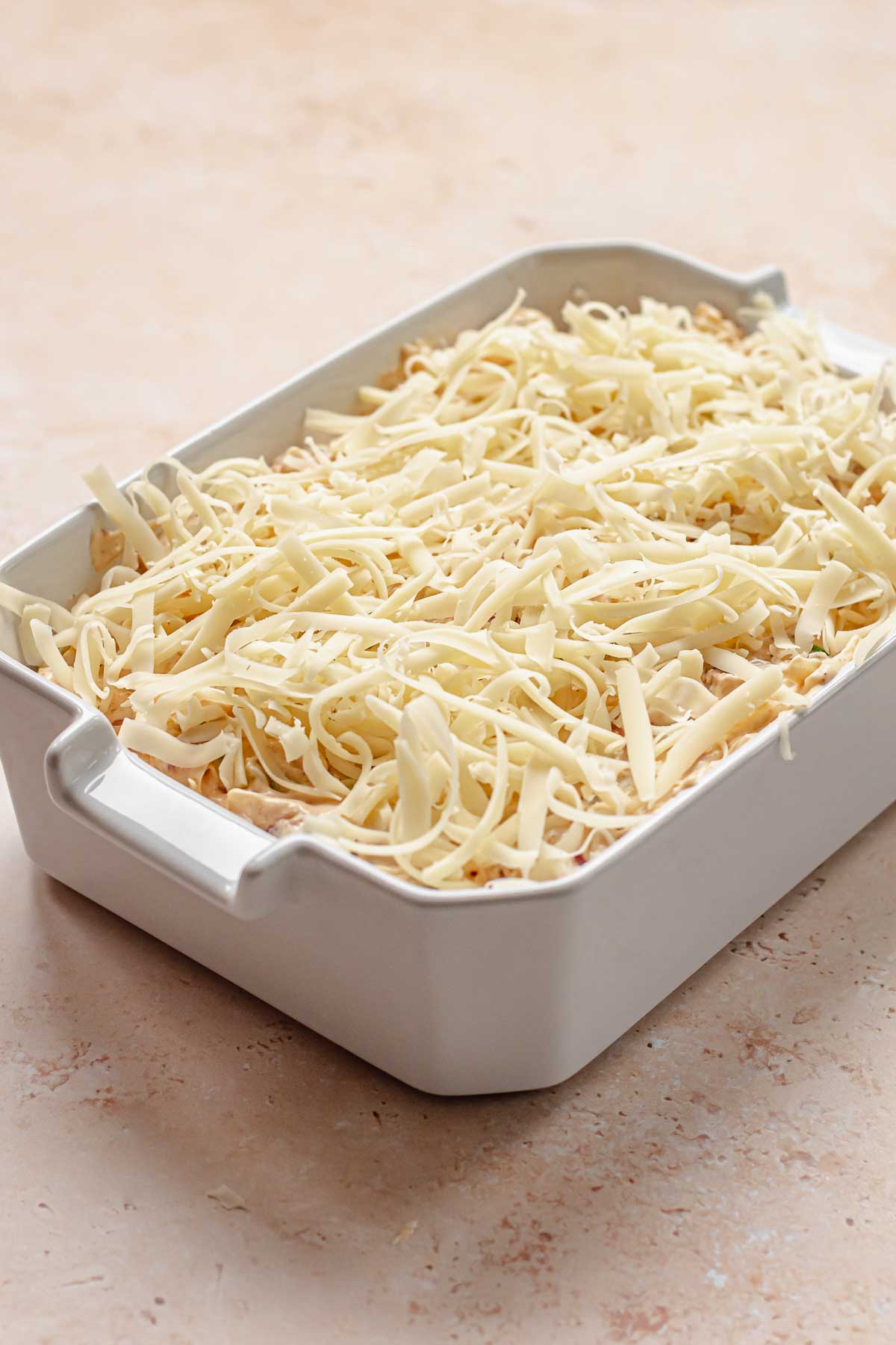 Pre-baked dip in a dish with shredded cheese on top.
