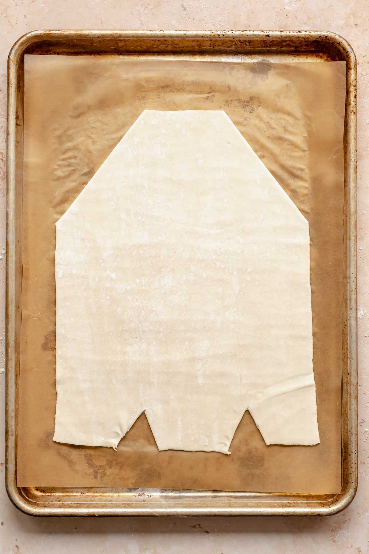 A cut a prepared danish base on a cookie sheet.