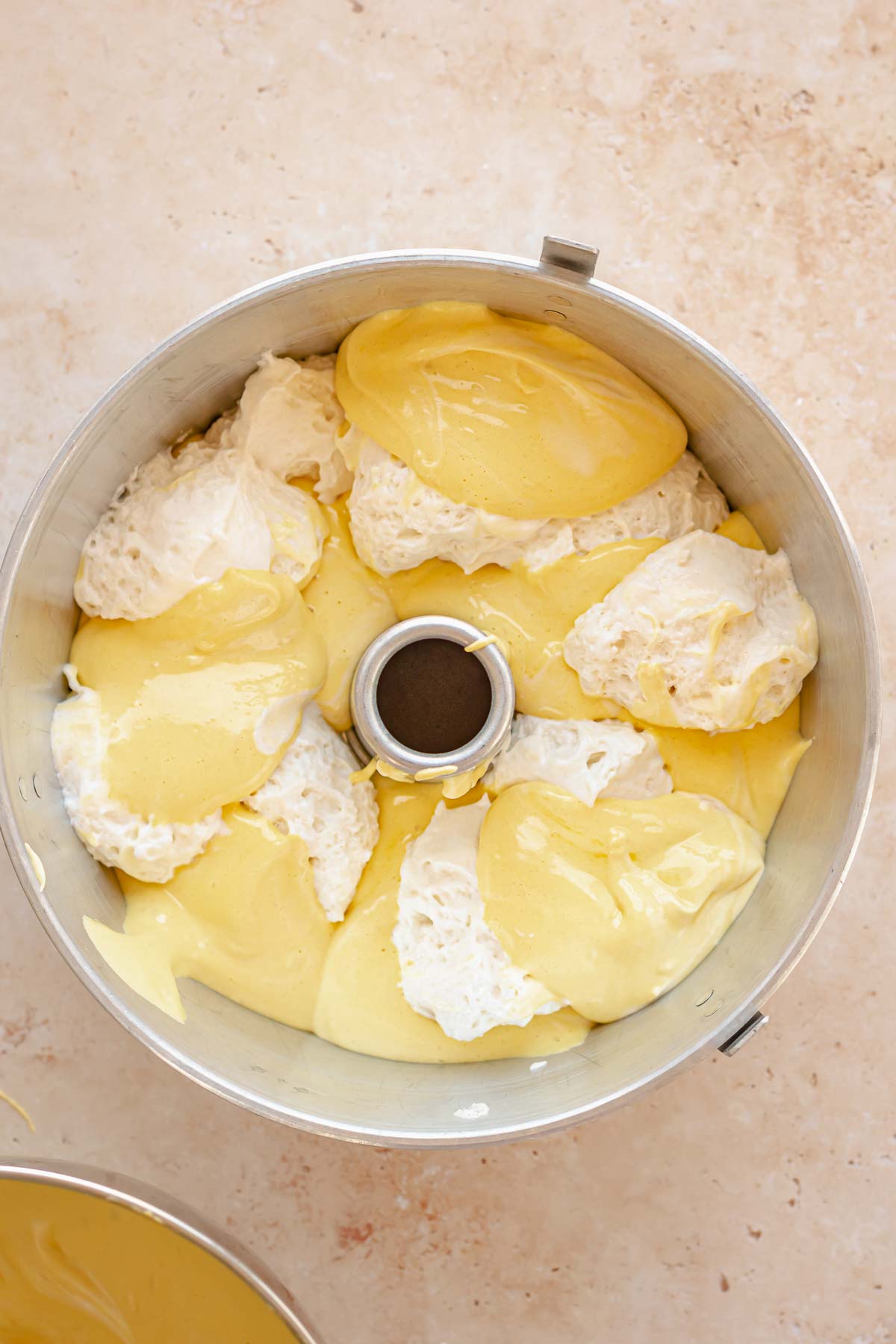 Yellow and white cake batter alternating in a tube pan.