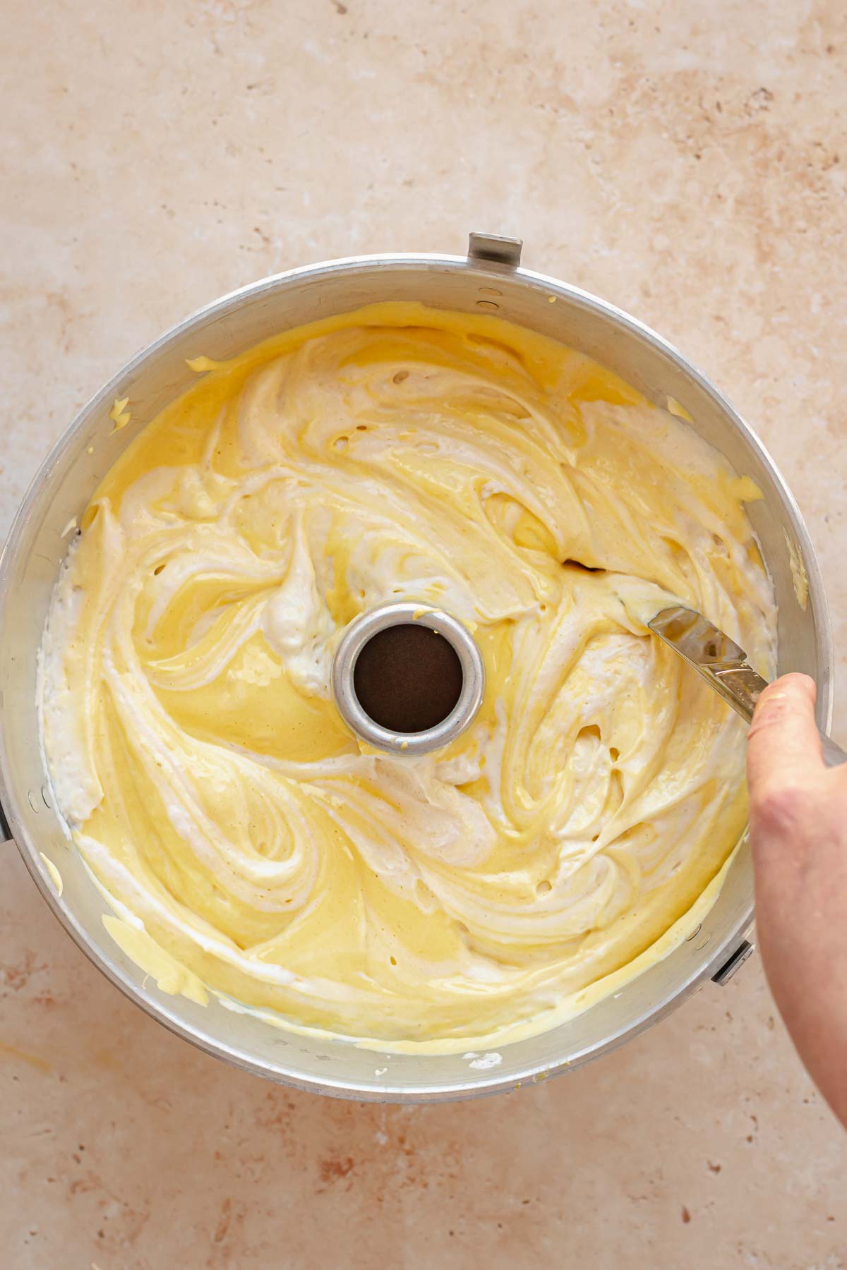 A knife swirls together the batters in the tube pan.