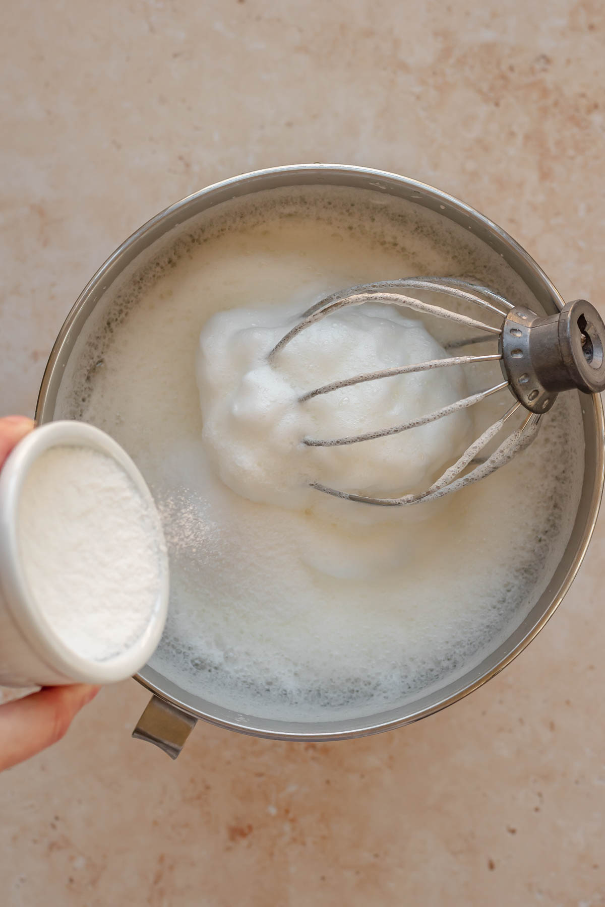 Pouring sugar into whipped egg whites.