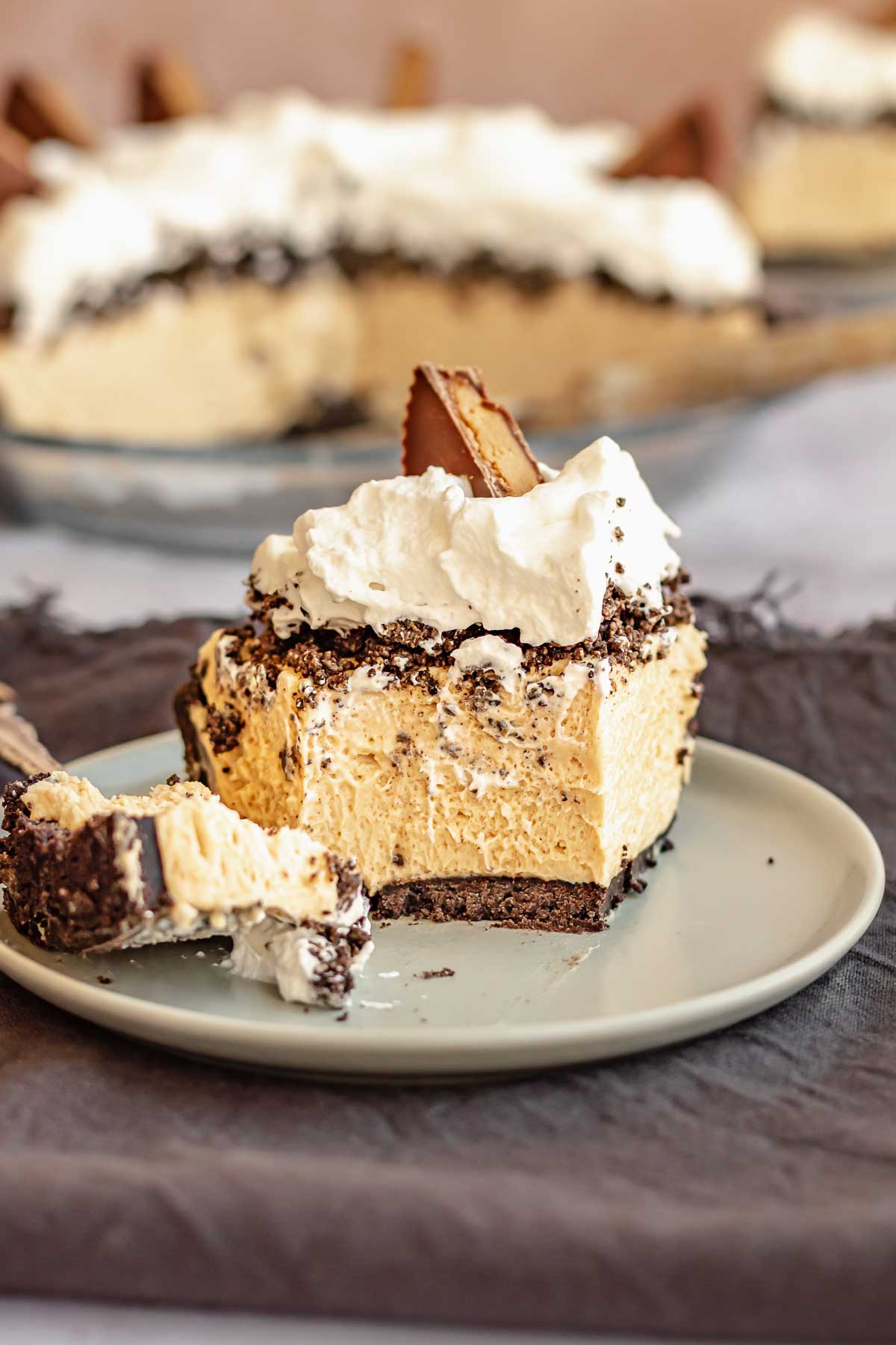 A slice of peanut butter oreo pie on a plate with a bite sitting on a fork.