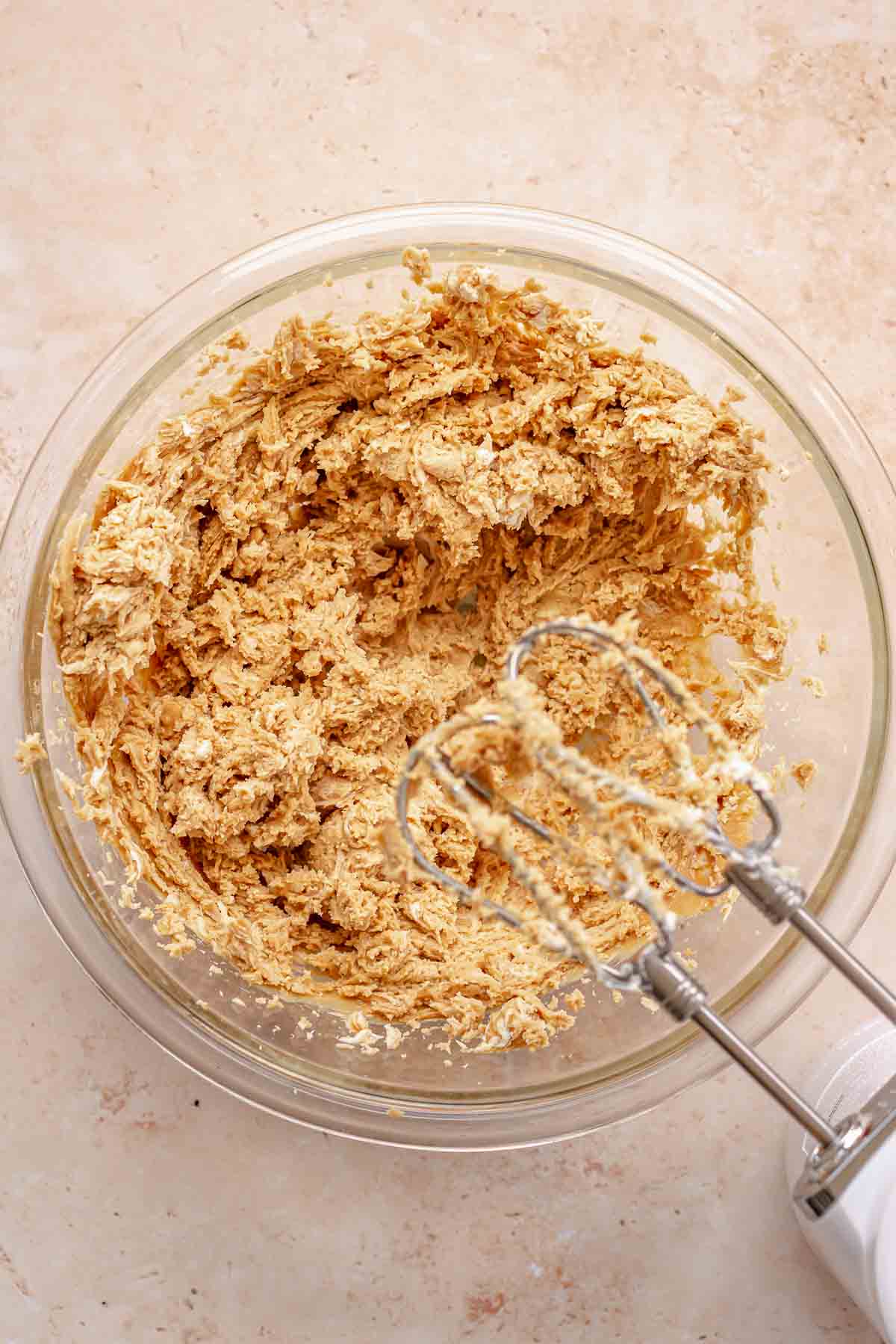 A hand mixer mixes together peanut butter and cream cheese in a bowl.