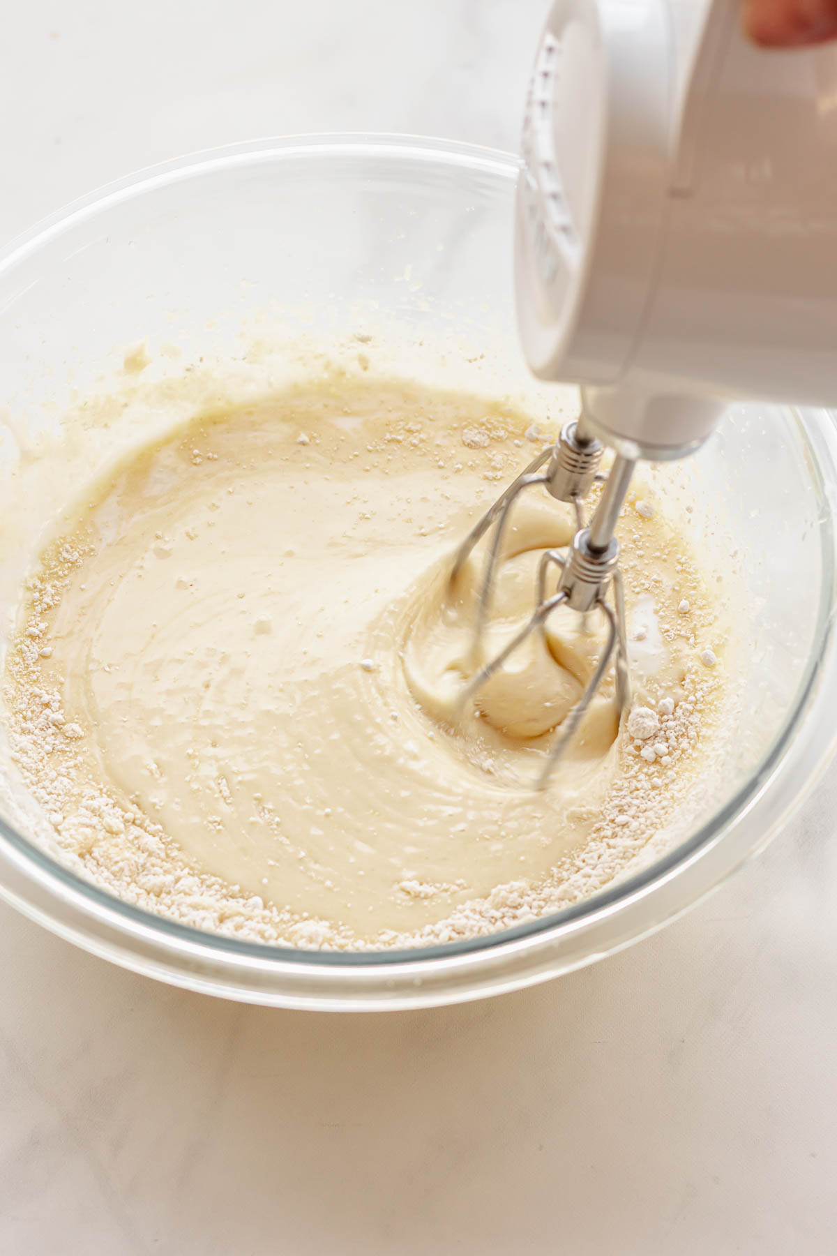 A hand mixer mixes in flour into cake batter.
