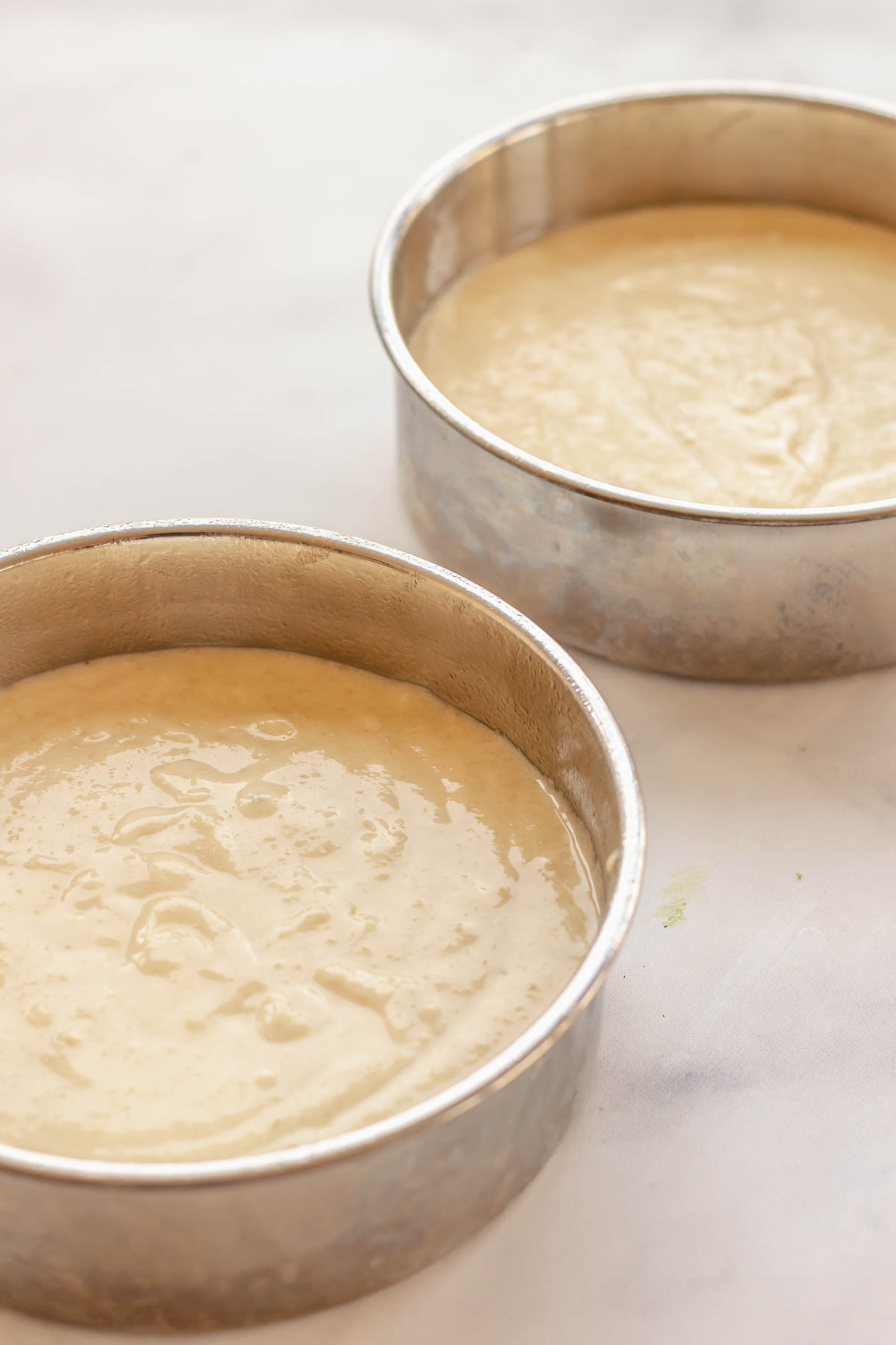 Almond cake batter in two cake pans.