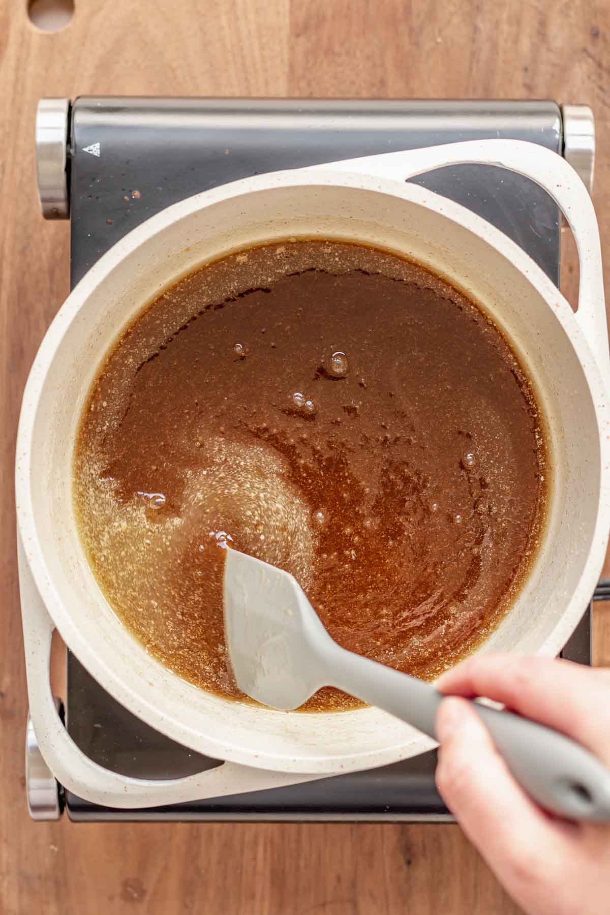 Brown sugar and butter being stirred in a pan.