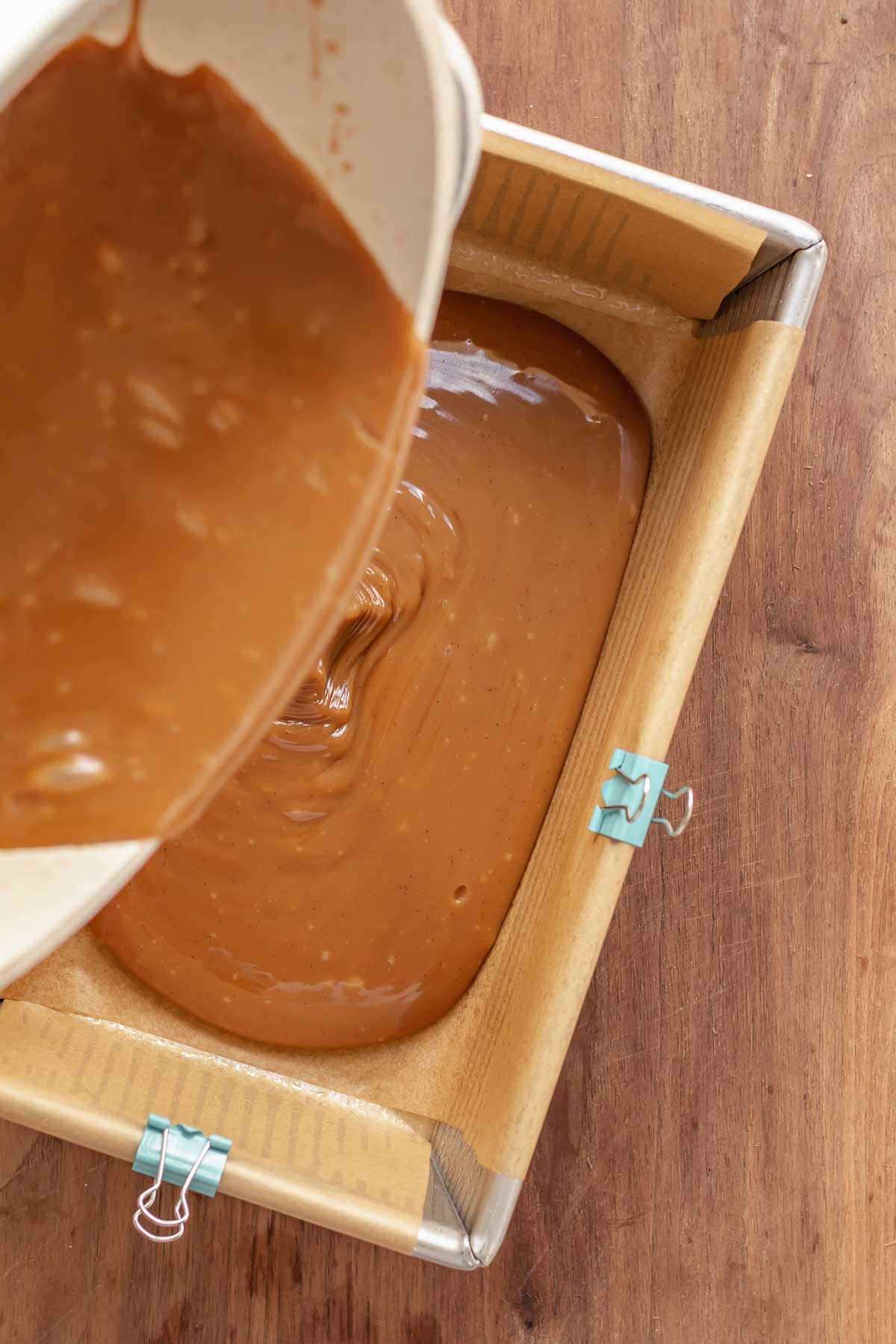 Caramel being poured into a prepared loaf pan.