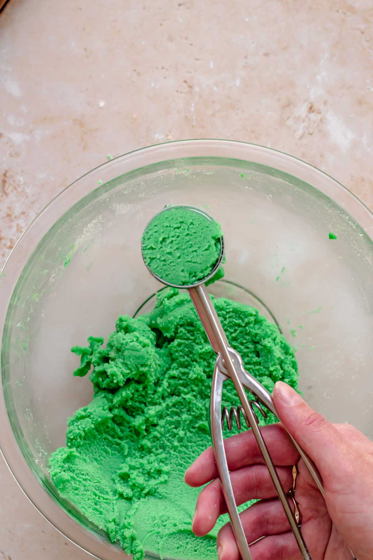 Green cookie dough in a cookie scoop.