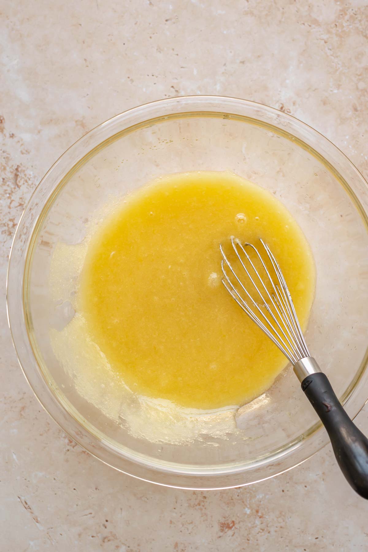 Eggs, sugar and oil in a bowl with a whisk.