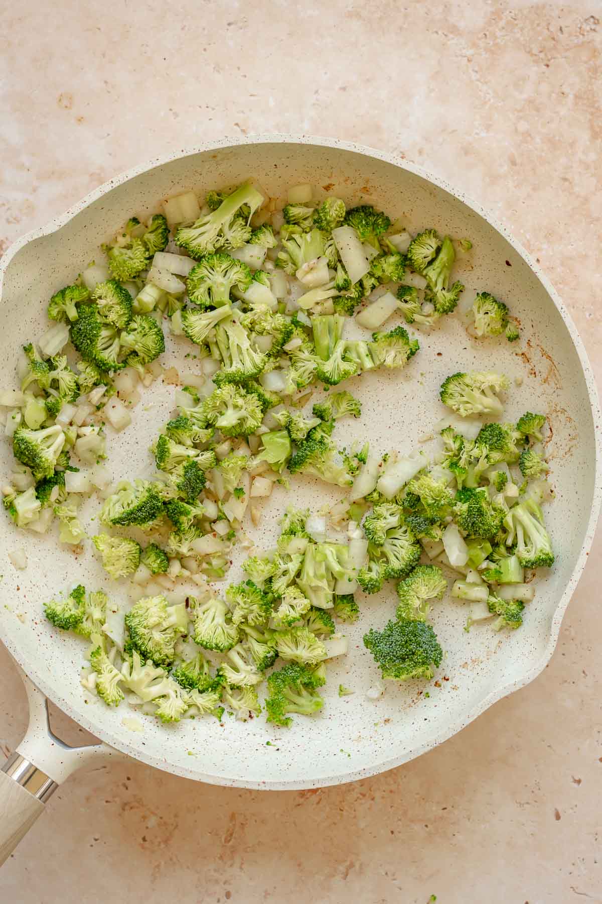 Broccoli, onion, and garlic sautéing in a pan.