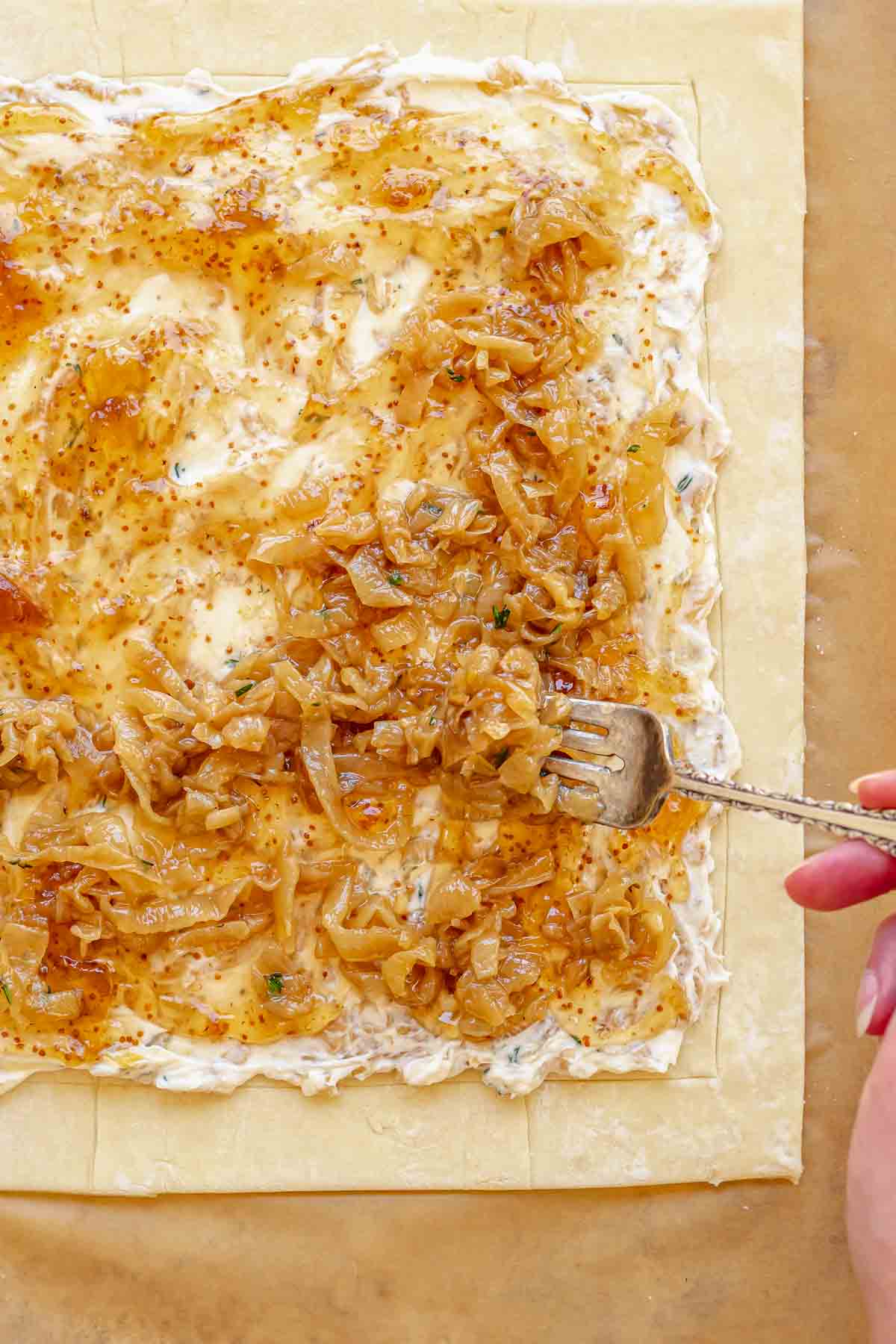 A fork adds caramelized onions to the top of the tart.