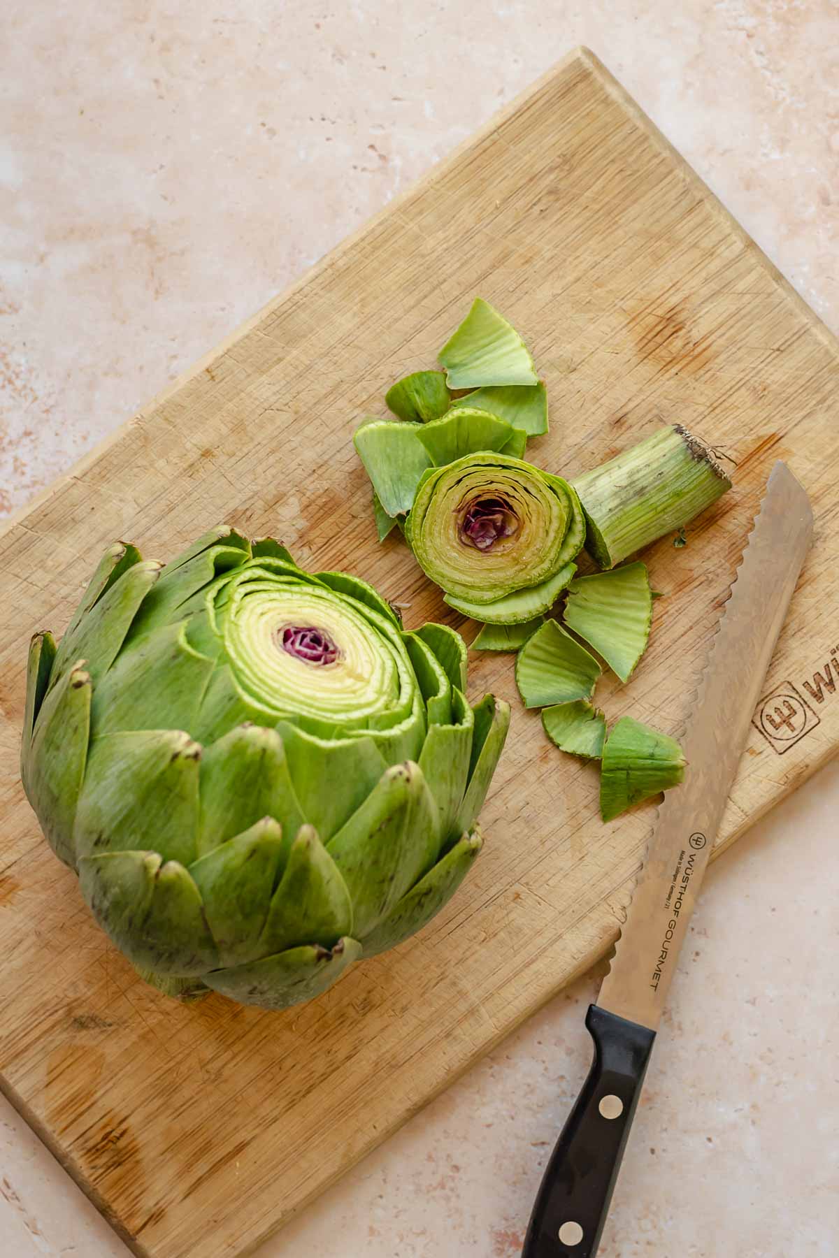 Artichoke with the top removed on a cutting board.