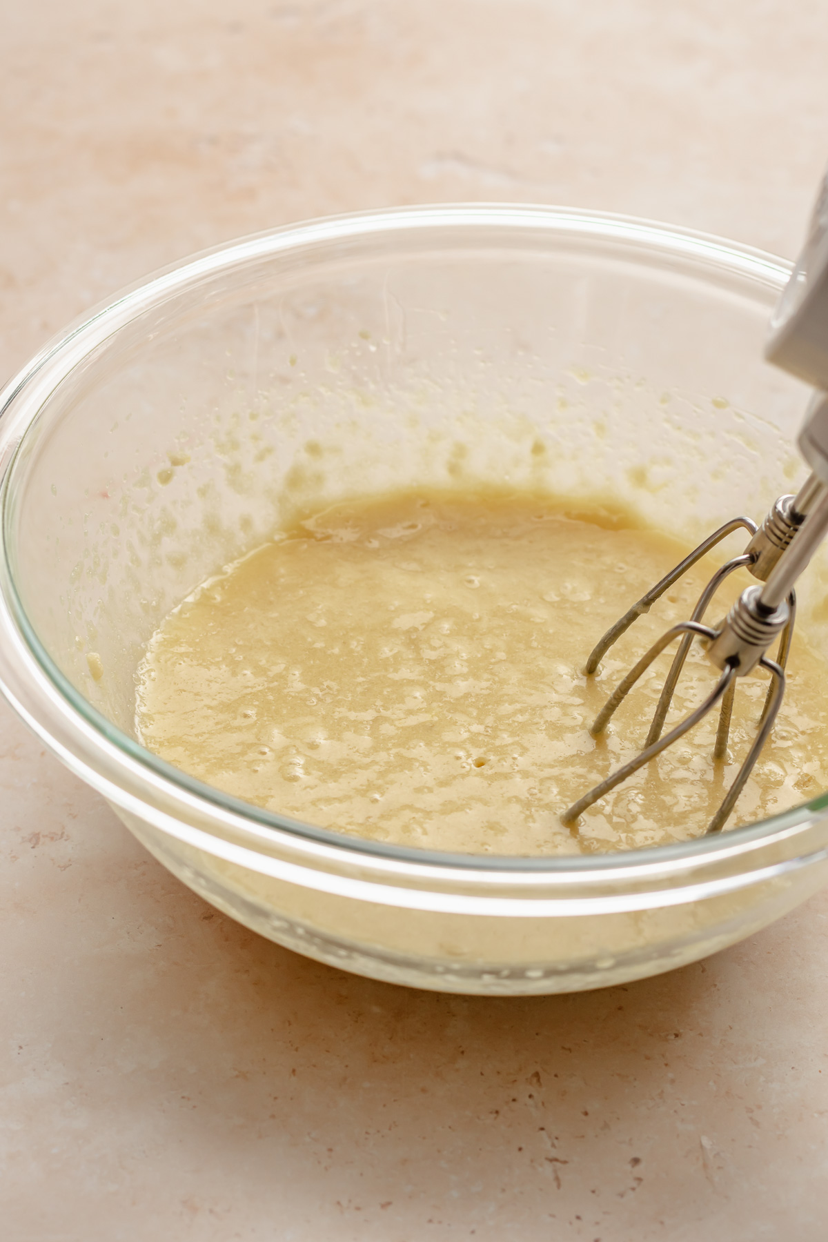 Beaters mixing cake batter in a bowl.