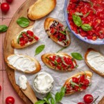 Goat cheese bruschetta on a board with fixings.