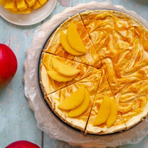 No bake mango cheesecake half sliced with mangoes on the slices.