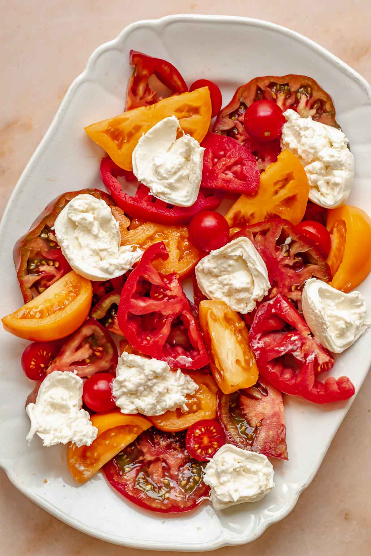 Tomatoes and torn burrata on a platter.