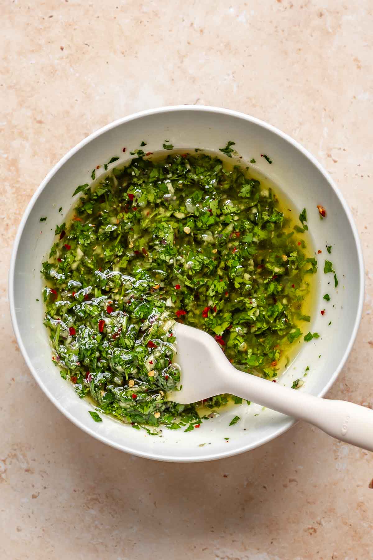 Chimichurri in a bowl with a spatula.