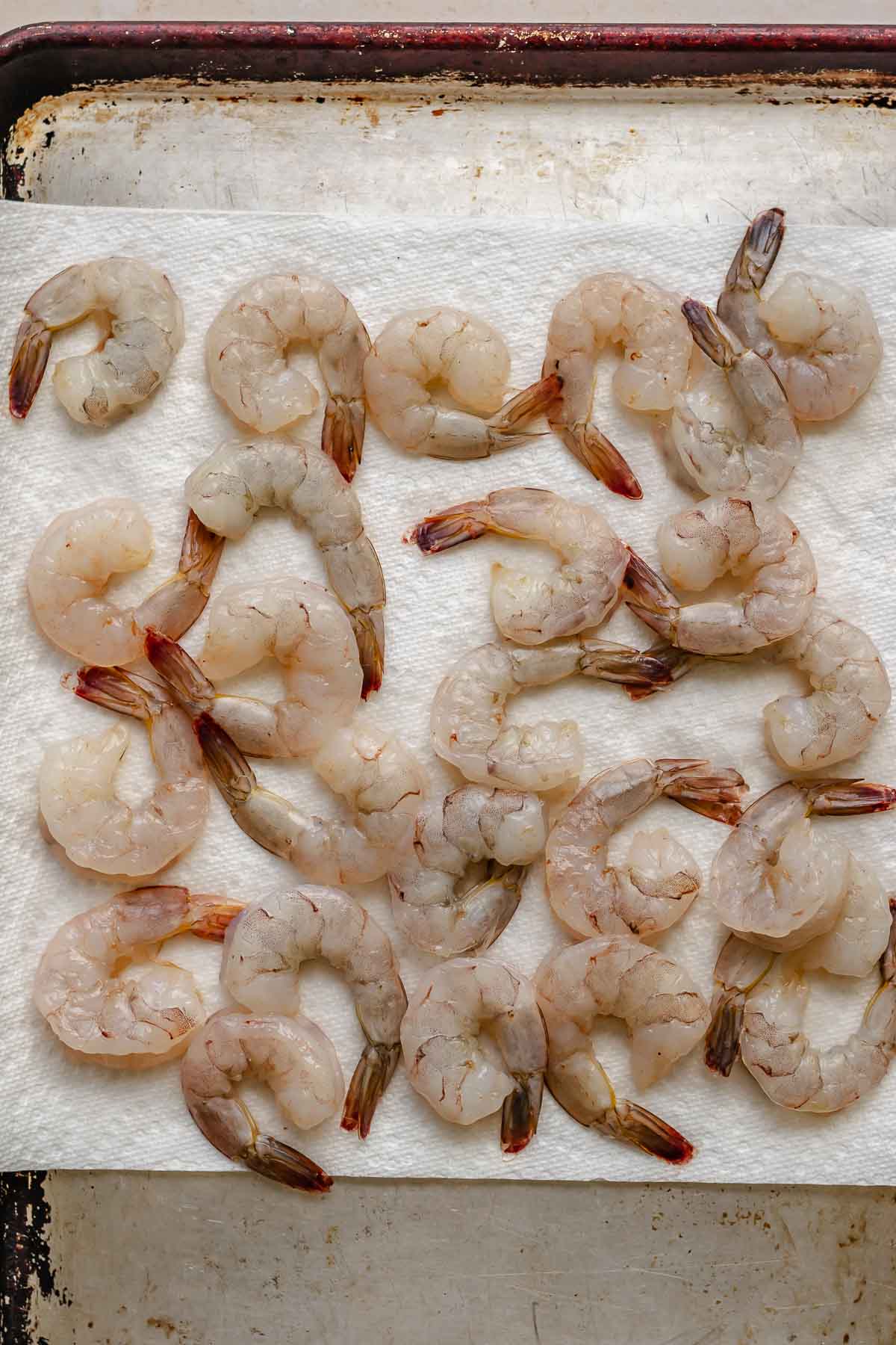 Raw, peeled shrimp on a paper towel with tails on.