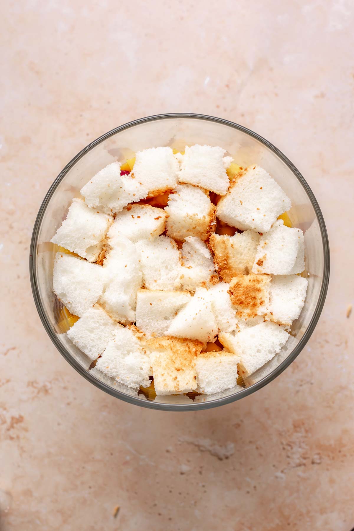 Angel food cake layer on top of fruit in a bowl.