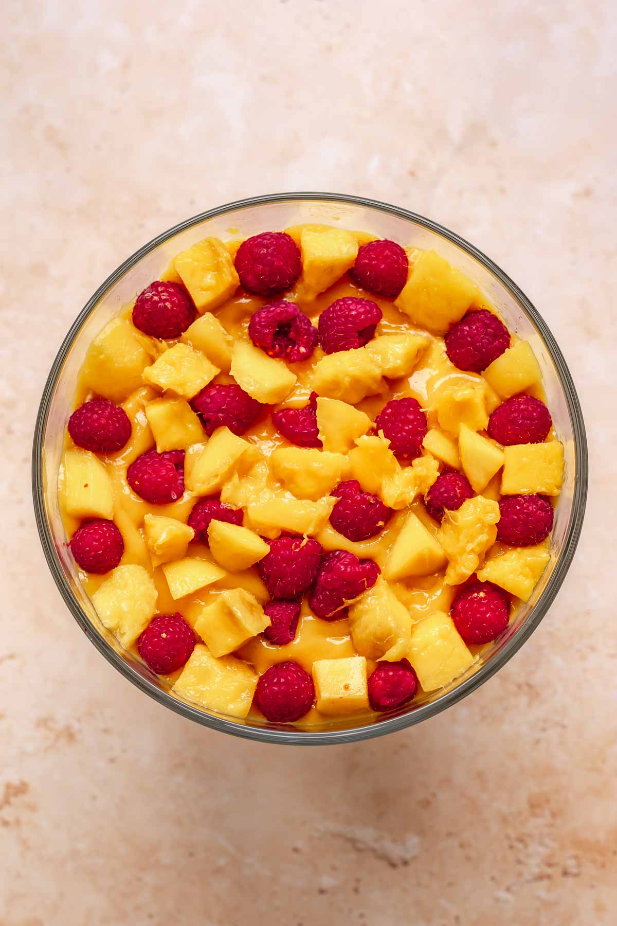 Mango and raspberries scattered in a trifle bowl.