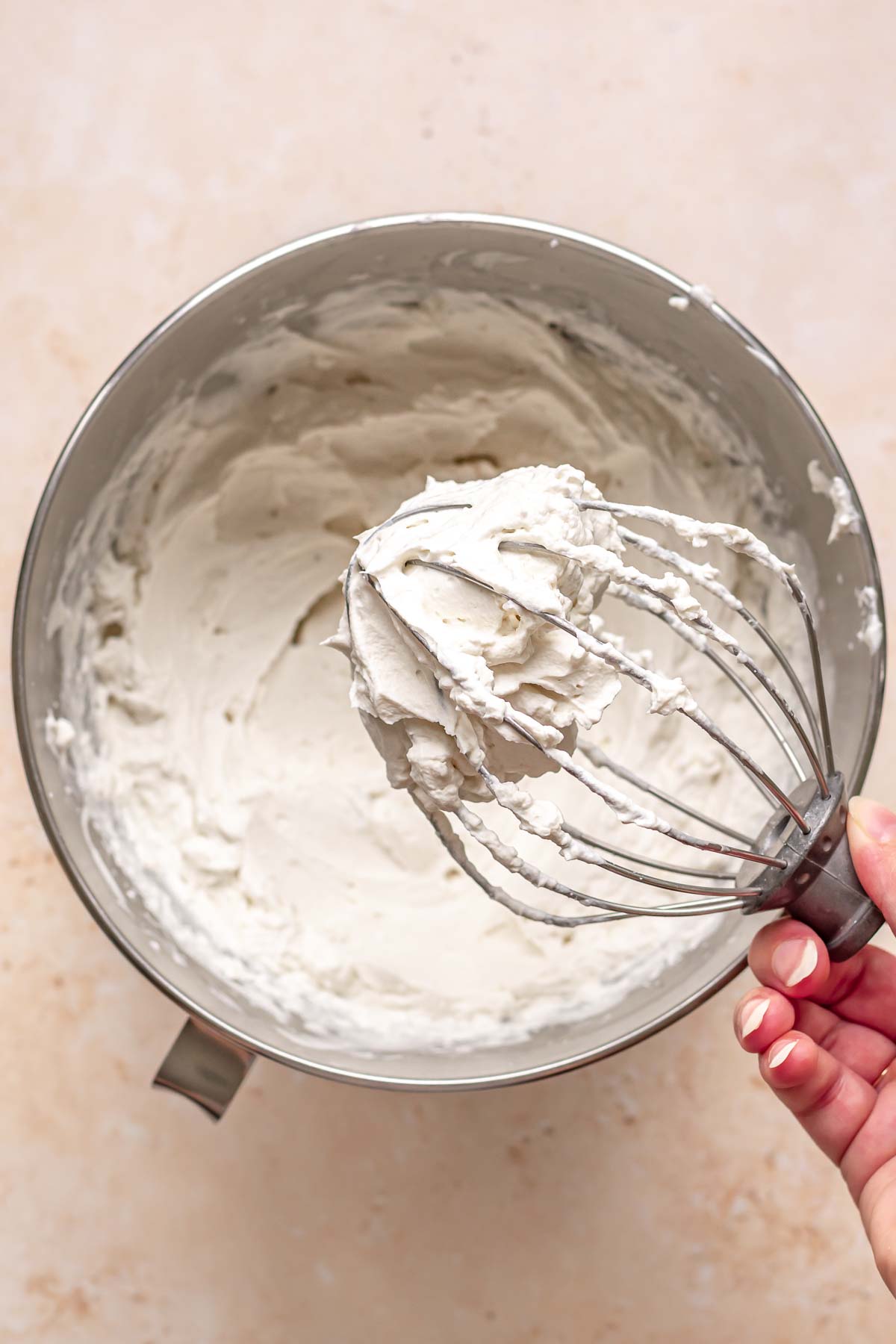 Coconut whipped cream on the tip of a whisk.