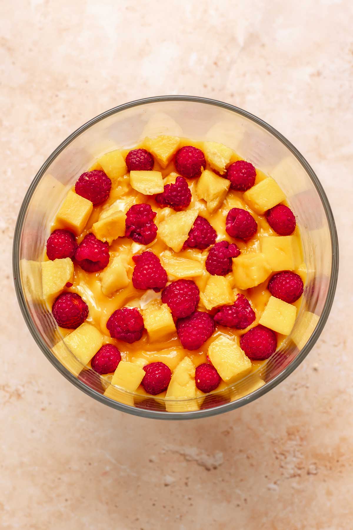 Mango and raspberries scattered in a trifle bowl.