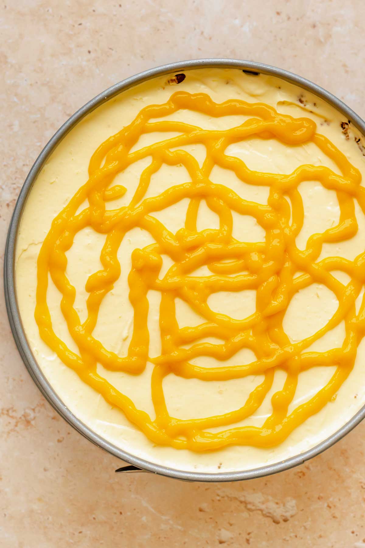 Mango puree is piped on top of cheesecake batter.