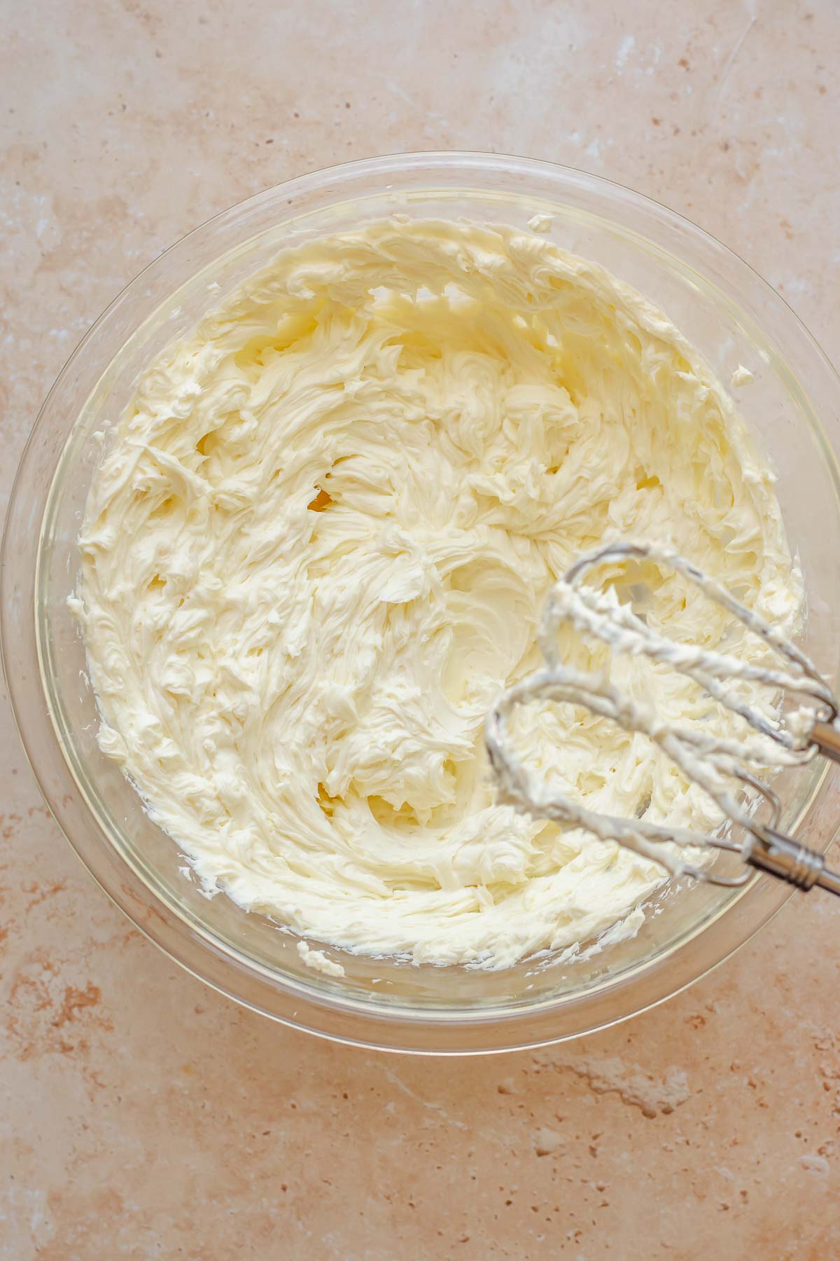 Beaters mix cream cheese in bowl.