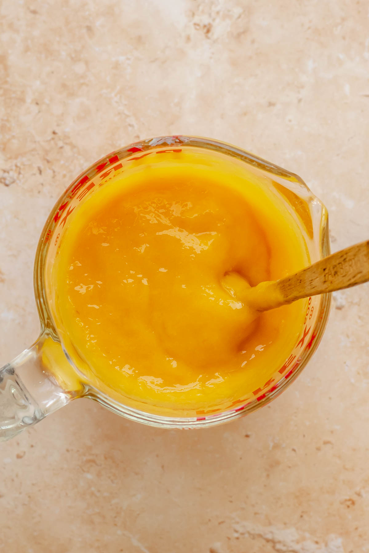 Mango puree mixed with gelatin in a measuring cup.