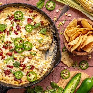 Jalapeno corn dip in a skillet with a spoon and chips on the side.