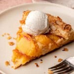 A slice of peach galette on a plate with a scoop of ice cream on top.