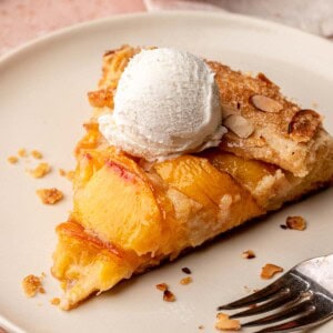A slice of peach galette on a plate with a scoop of ice cream on top.
