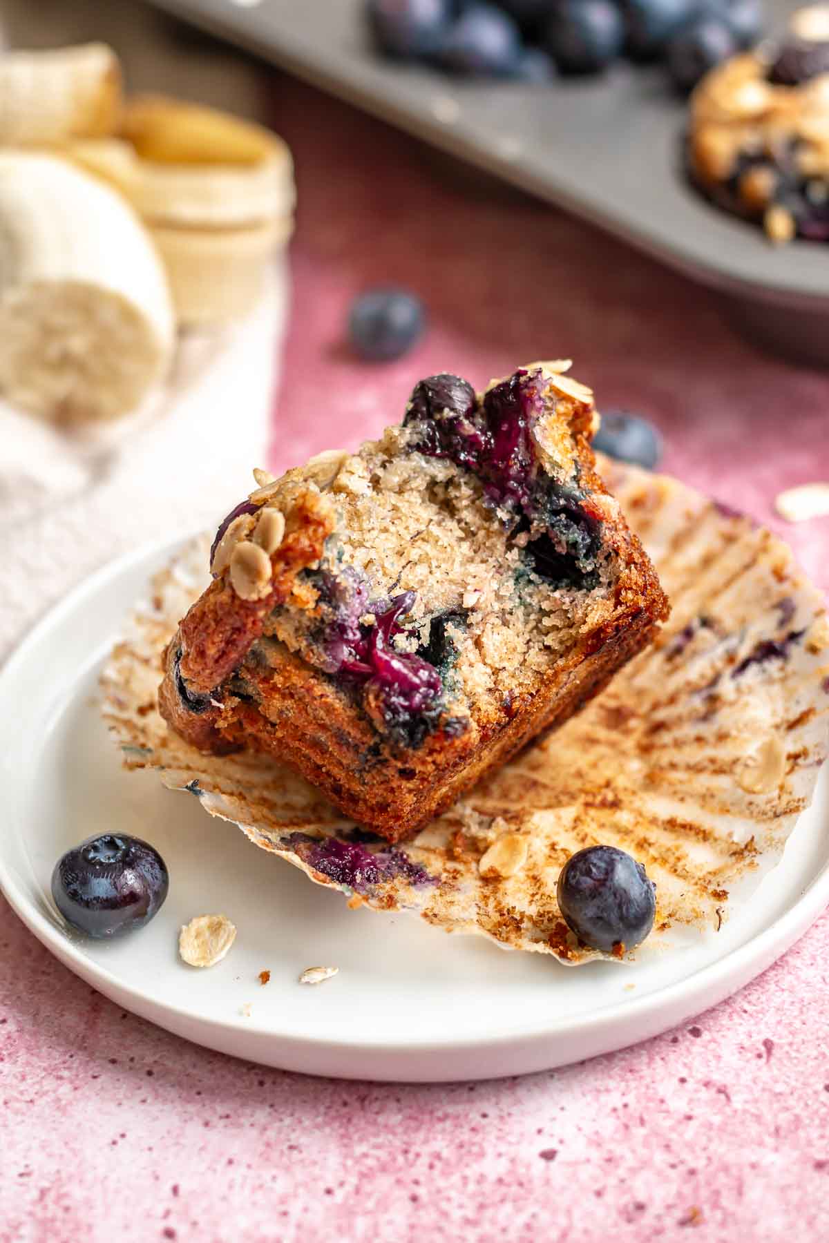Blueberry muffin on a plate with a bite removed.