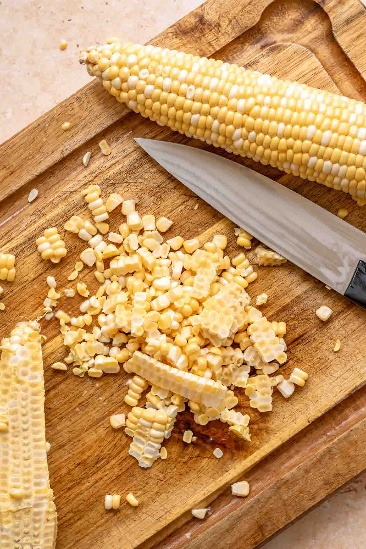 Corn sliced off the cob on a cutting board.