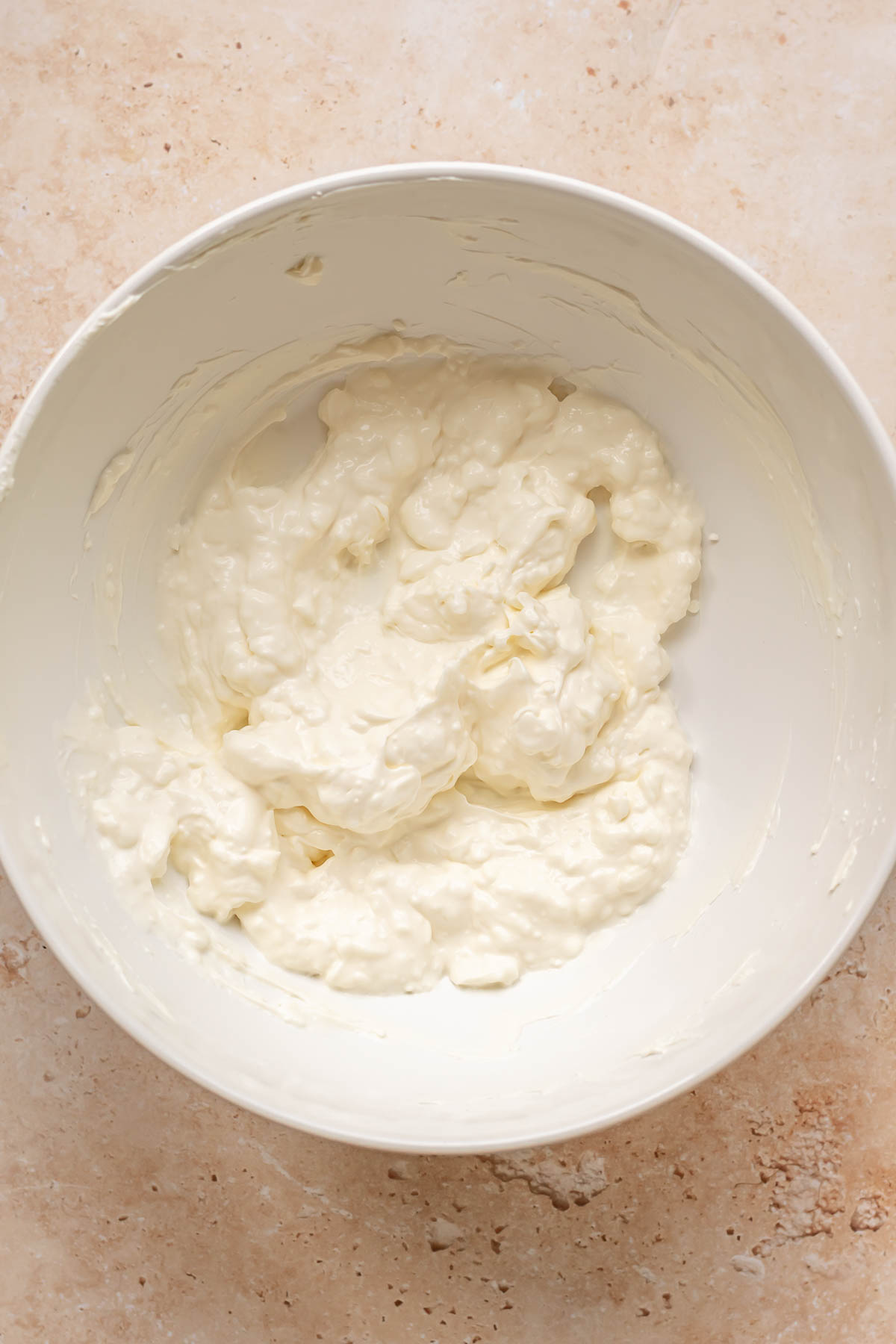 Cream cheese, mayonnaise and sour cream mixed in a bowl.