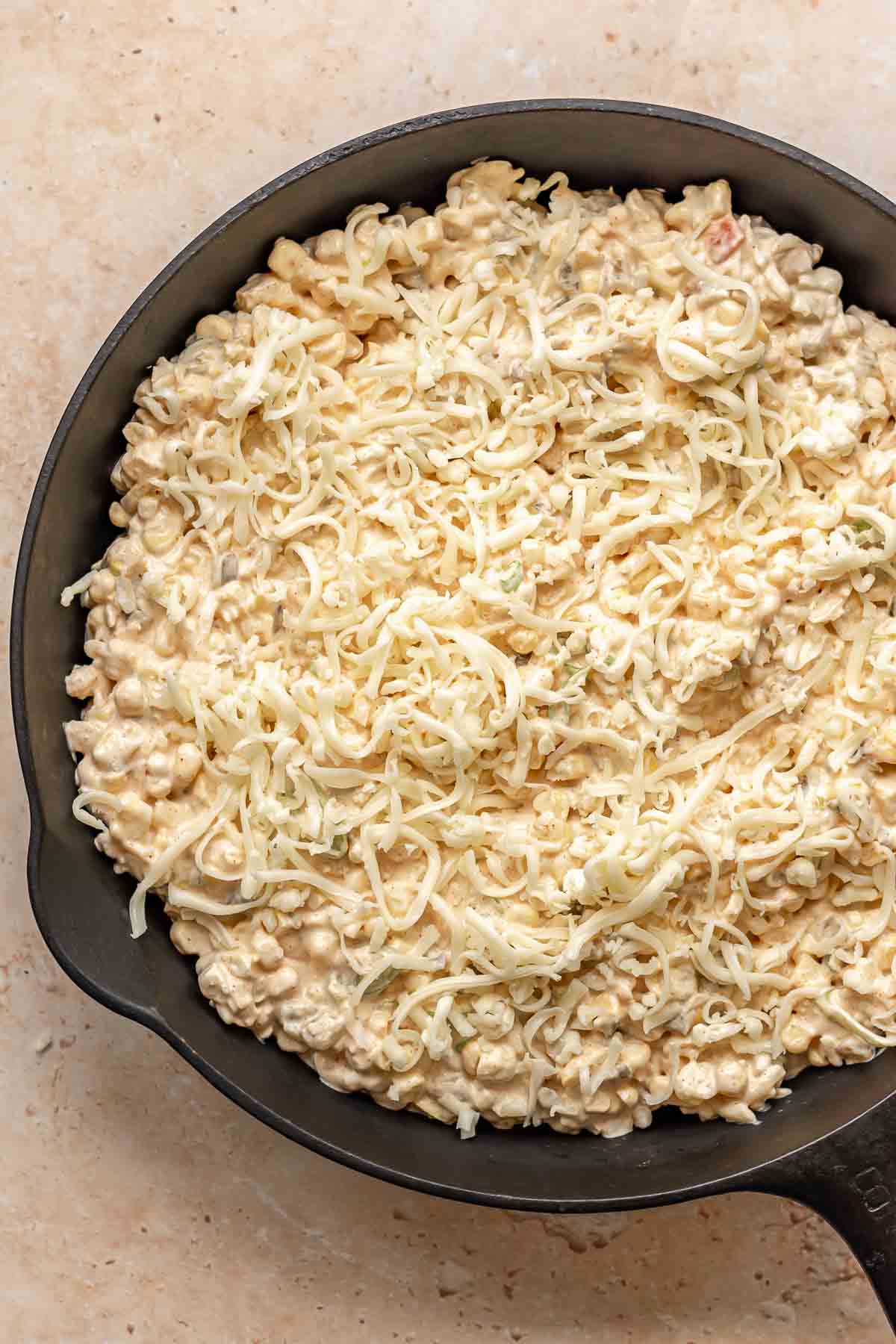 Corn dip in a skillet with shredded cheese on top.