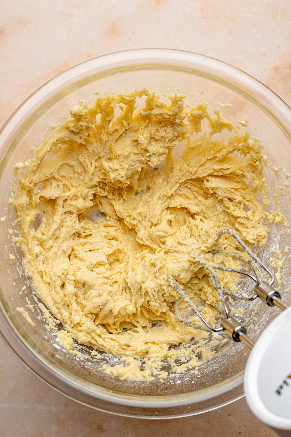A hand mixer mixes frangipane in a bowl.