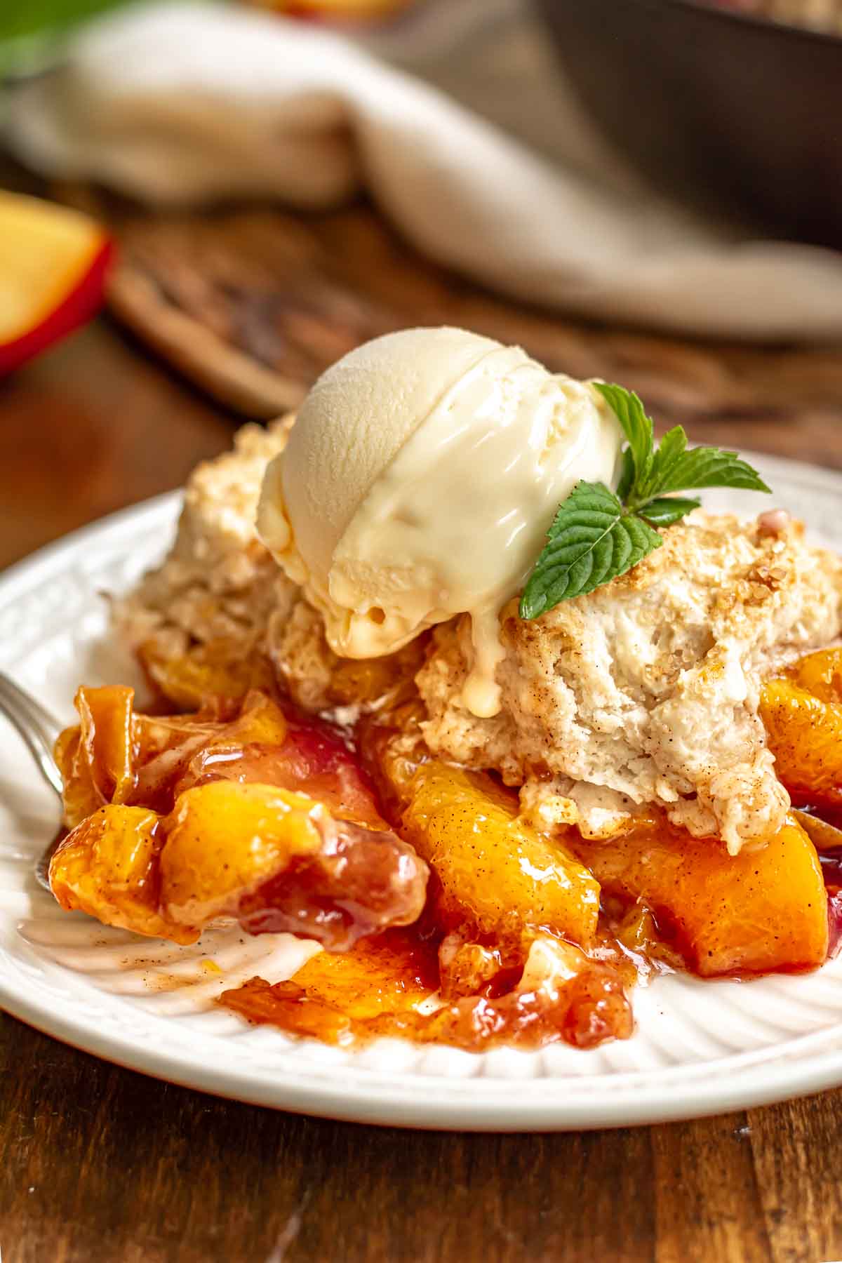 A plate with served peach cobbler topped with ice cream.