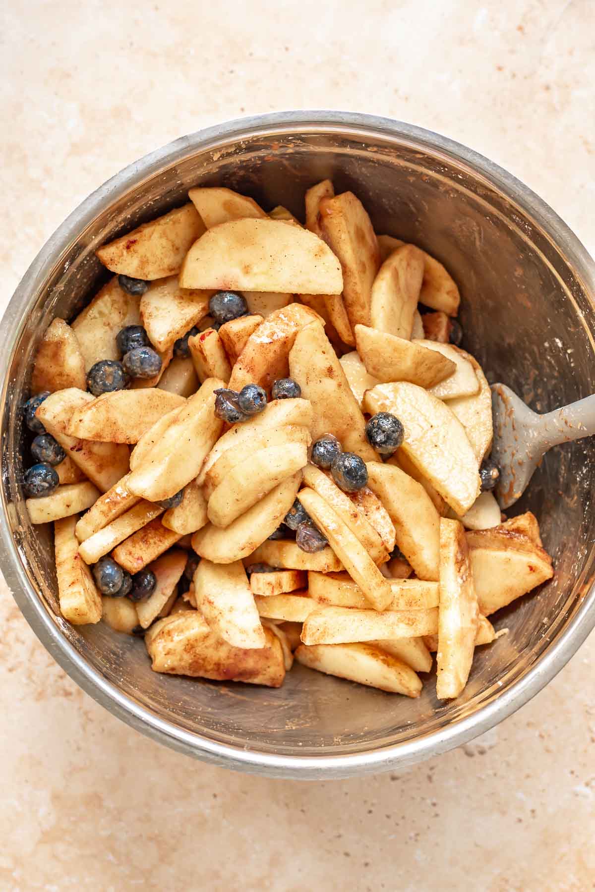 Sliced apples and blueberries in a mixing bowl.