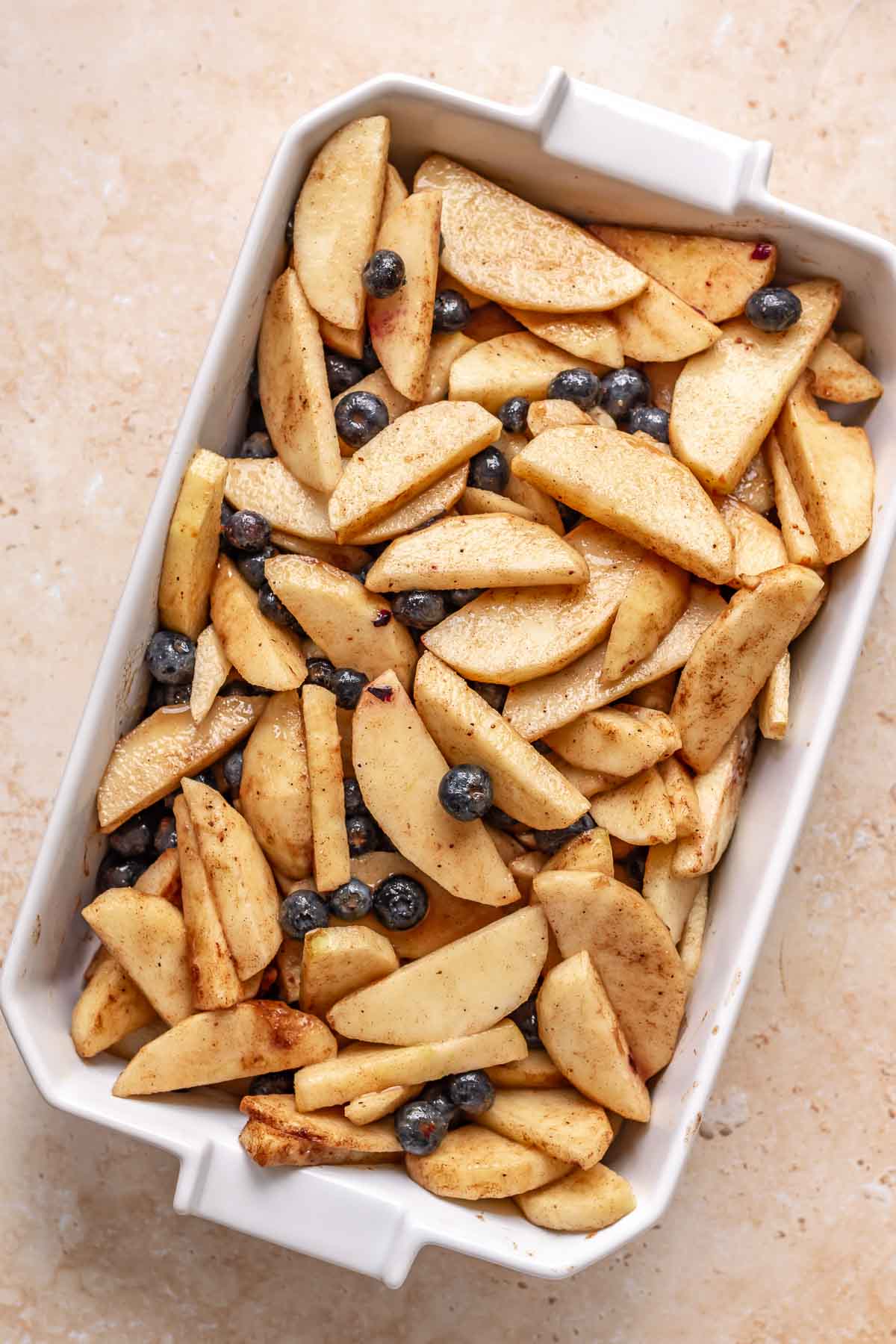 Apples and blueberries with spices in a casserole dish.