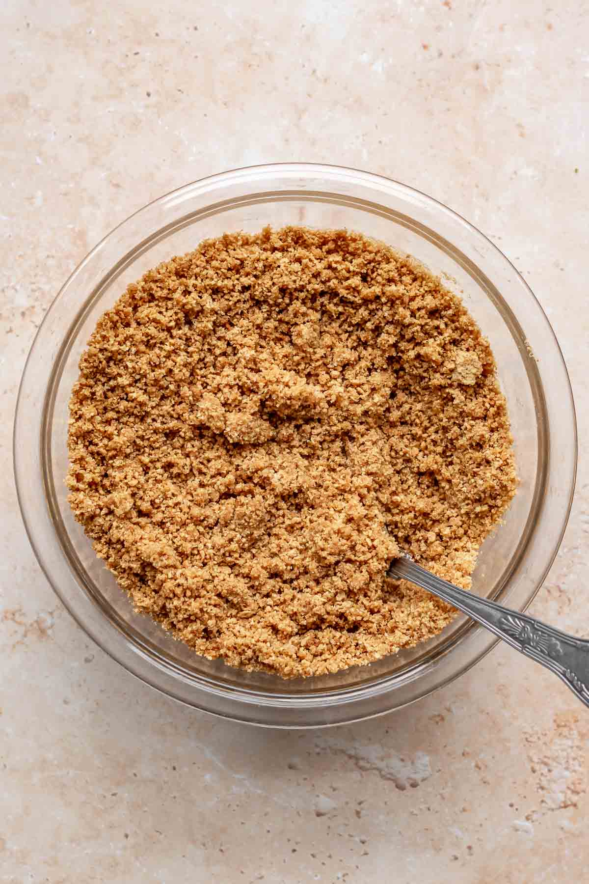 Graham cracker crumbs mixed in a bowl with a fork.