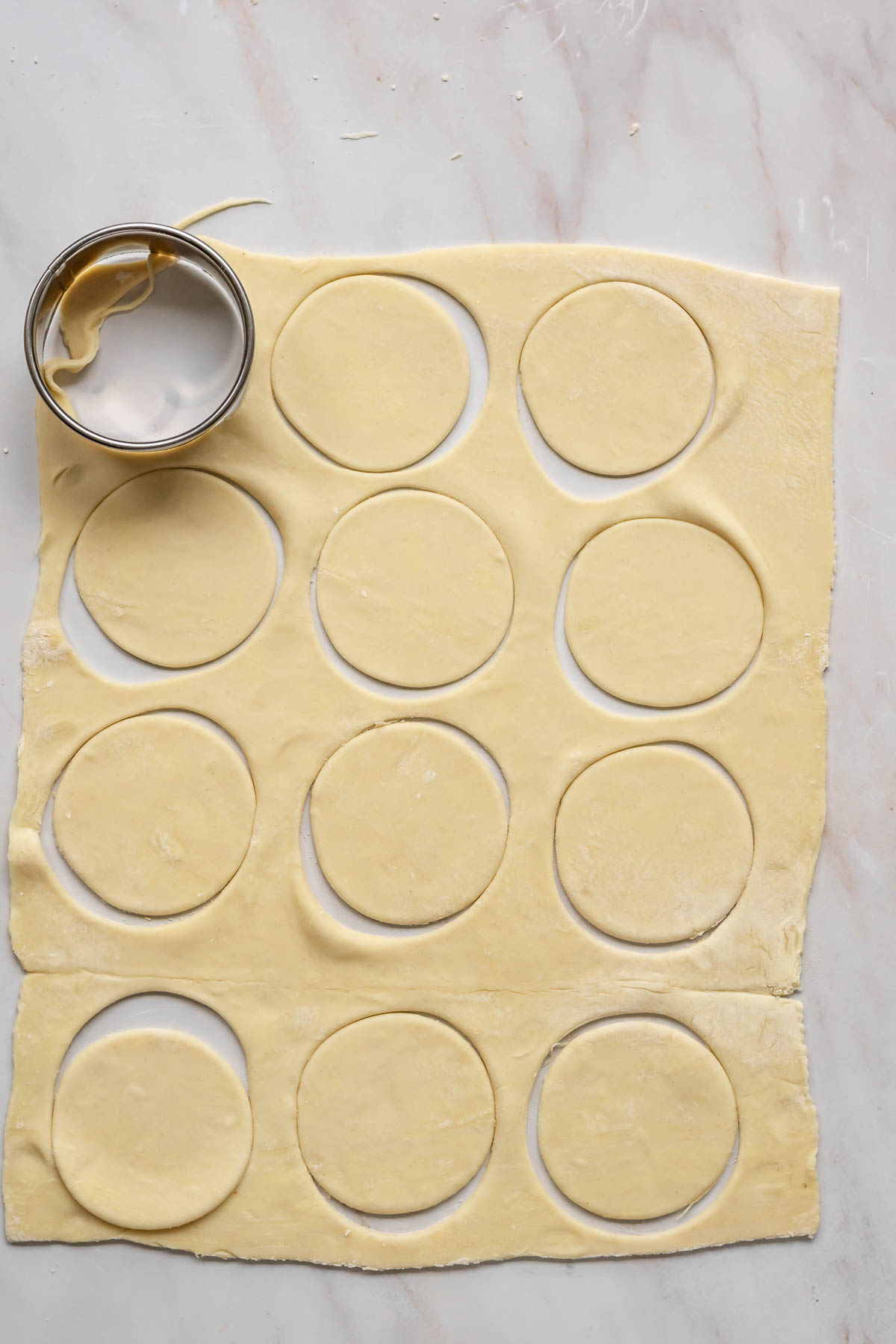 A biscuit cutter cuts out rounds of puff pastry.