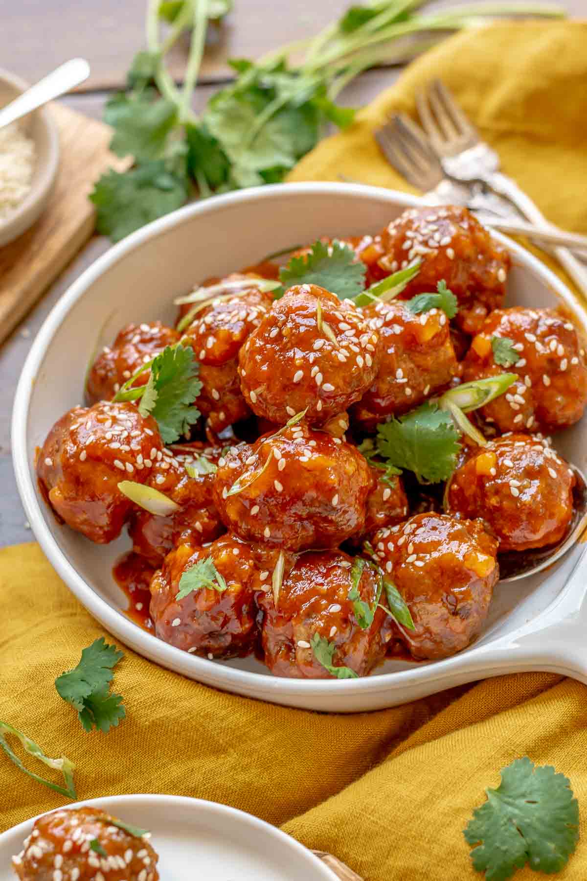 A garnished bowl of honey sriracha meatballs.