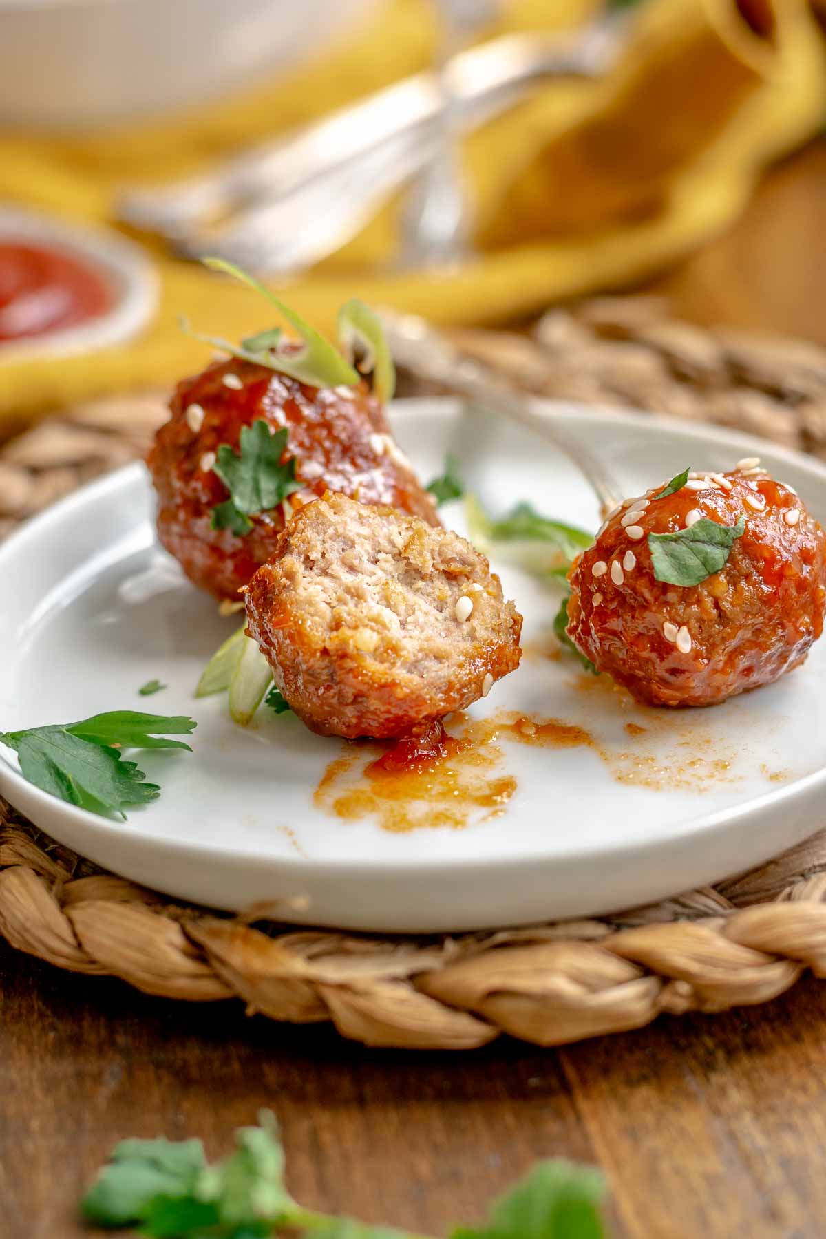 Honey sriracha meatballs on a plate. One is broken open to show the center.